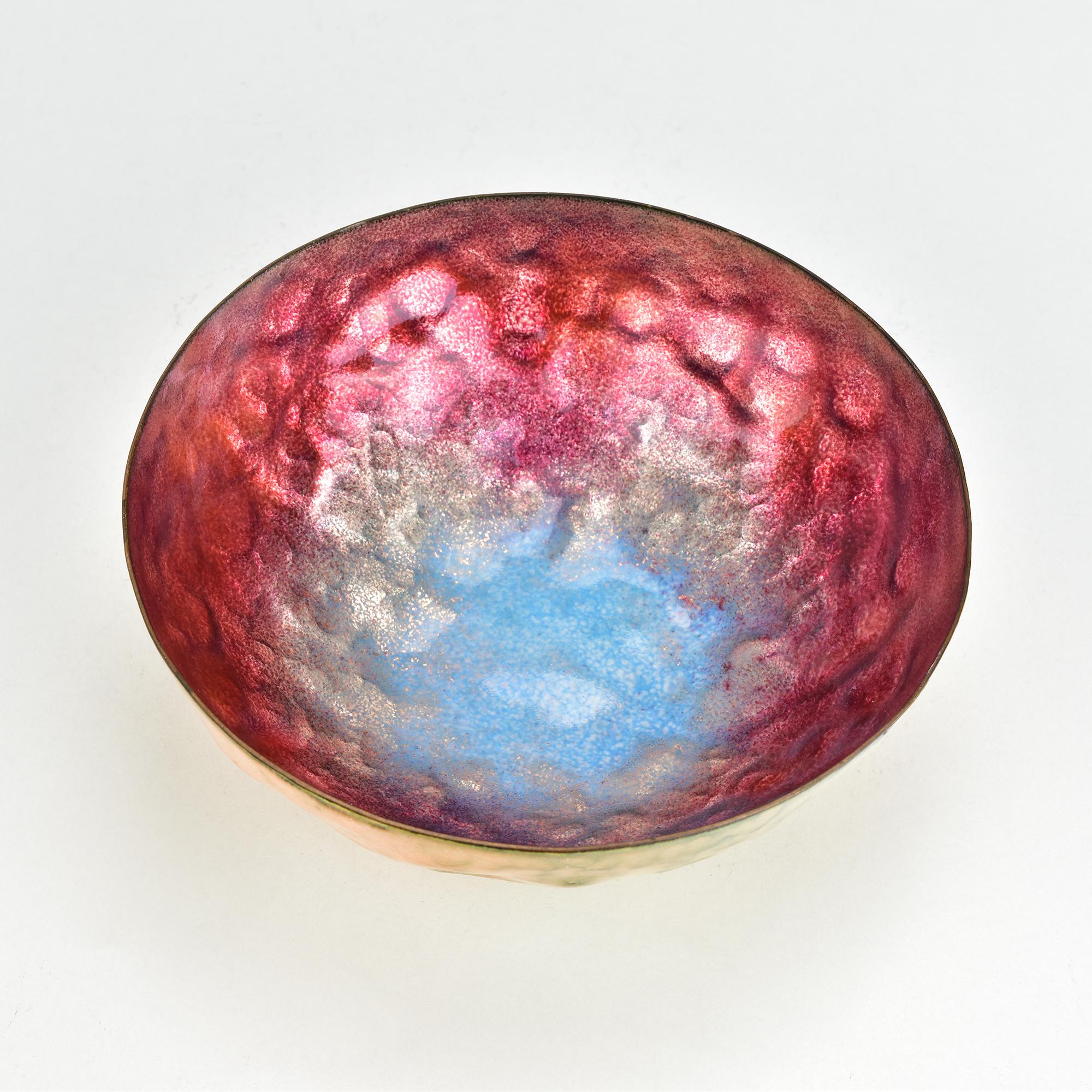 This striking enameled copper bowl by renowned Italian designer Paolo De Poli showcases the vibrant artistry characteristic of the Mid-Century Modern era. The bowl features a captivating, hand-hammered texture with an iridescent enamel interior in