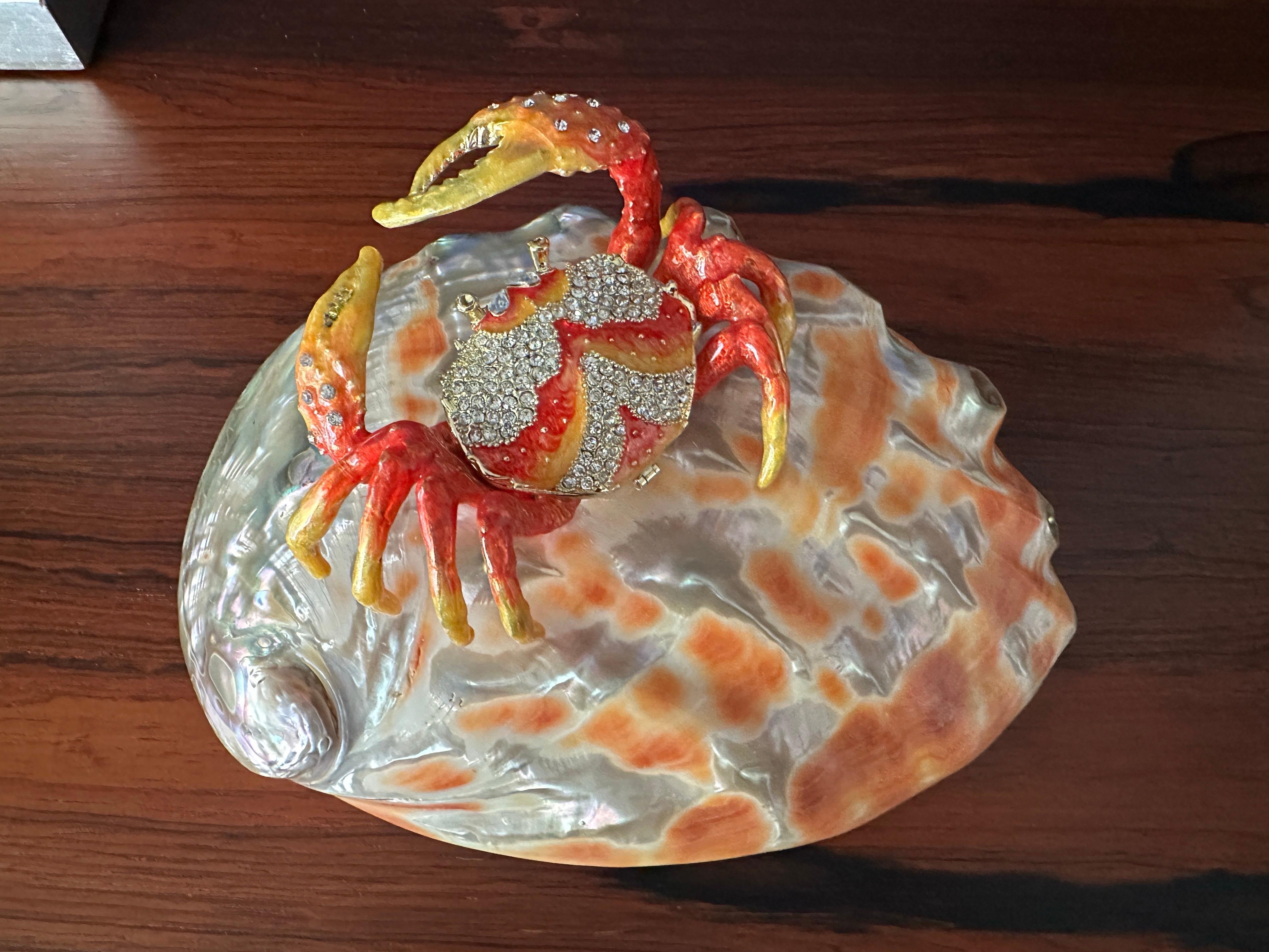Enameled metal crab sculpture with secret compartment and rhinestones mounted on pink salmon polished abalone shell made in the style of Jay Strongwater or Tony Duquette.
Only crab is 4