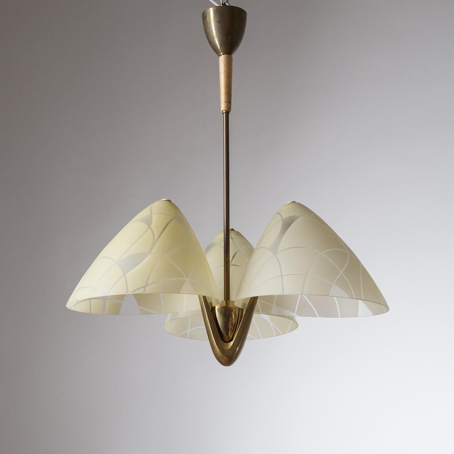 Rare Art Deco brass chandelier with large enameled glass diffusers from the 1940s. The large cone-shaped blown glass diffusers have a satin finish with an abstract pattern enameled in a pale yellow. Each glass houses one original brass and ceramic