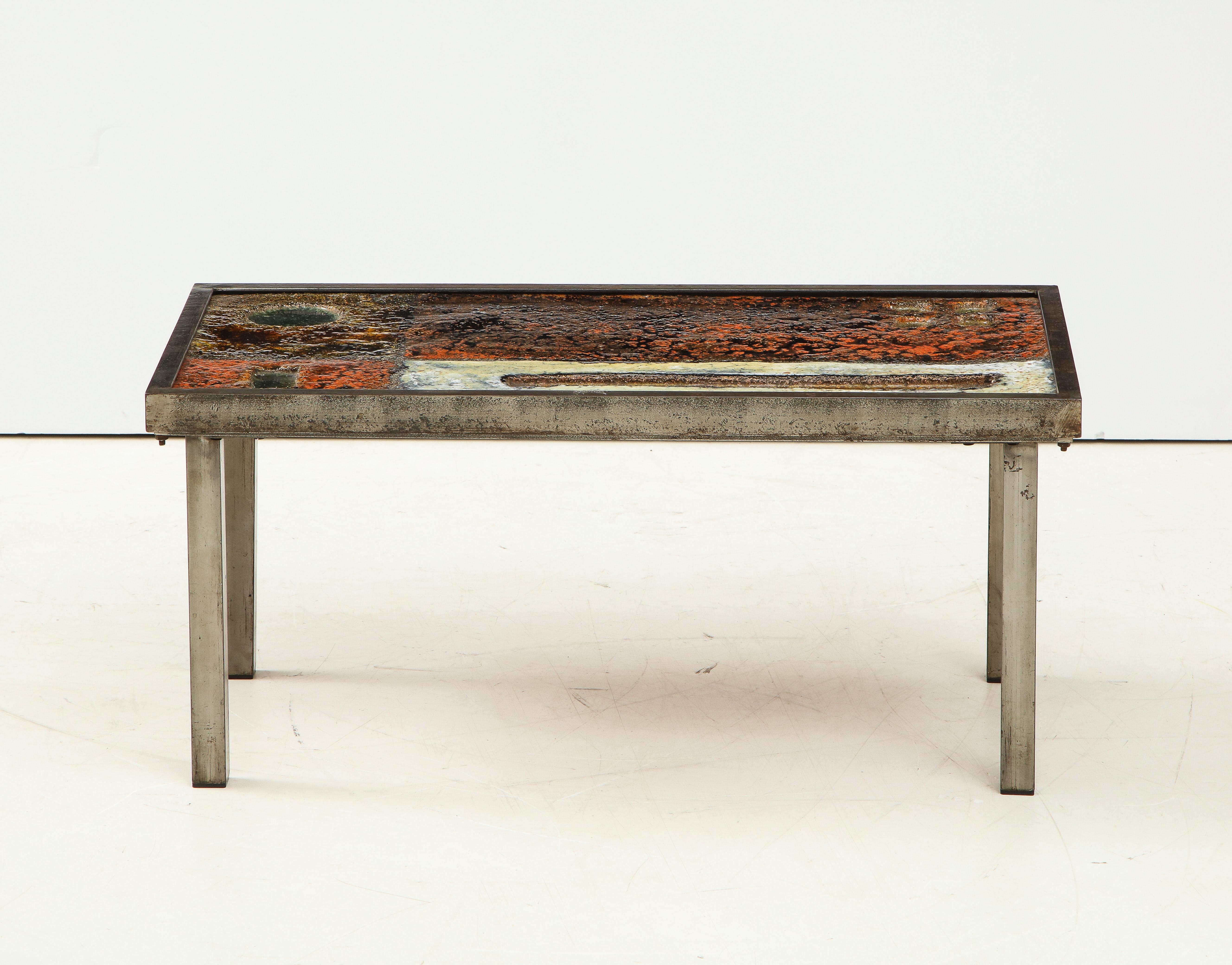 Rare low coffee table by Robert and Jean Cloutier, France, circa 1950. 

This coffee table consists of brushed steel legs and a stunning enameled lava top with an explosive design that invokes the painterly feats of Abstract Expressionism. Its warm,