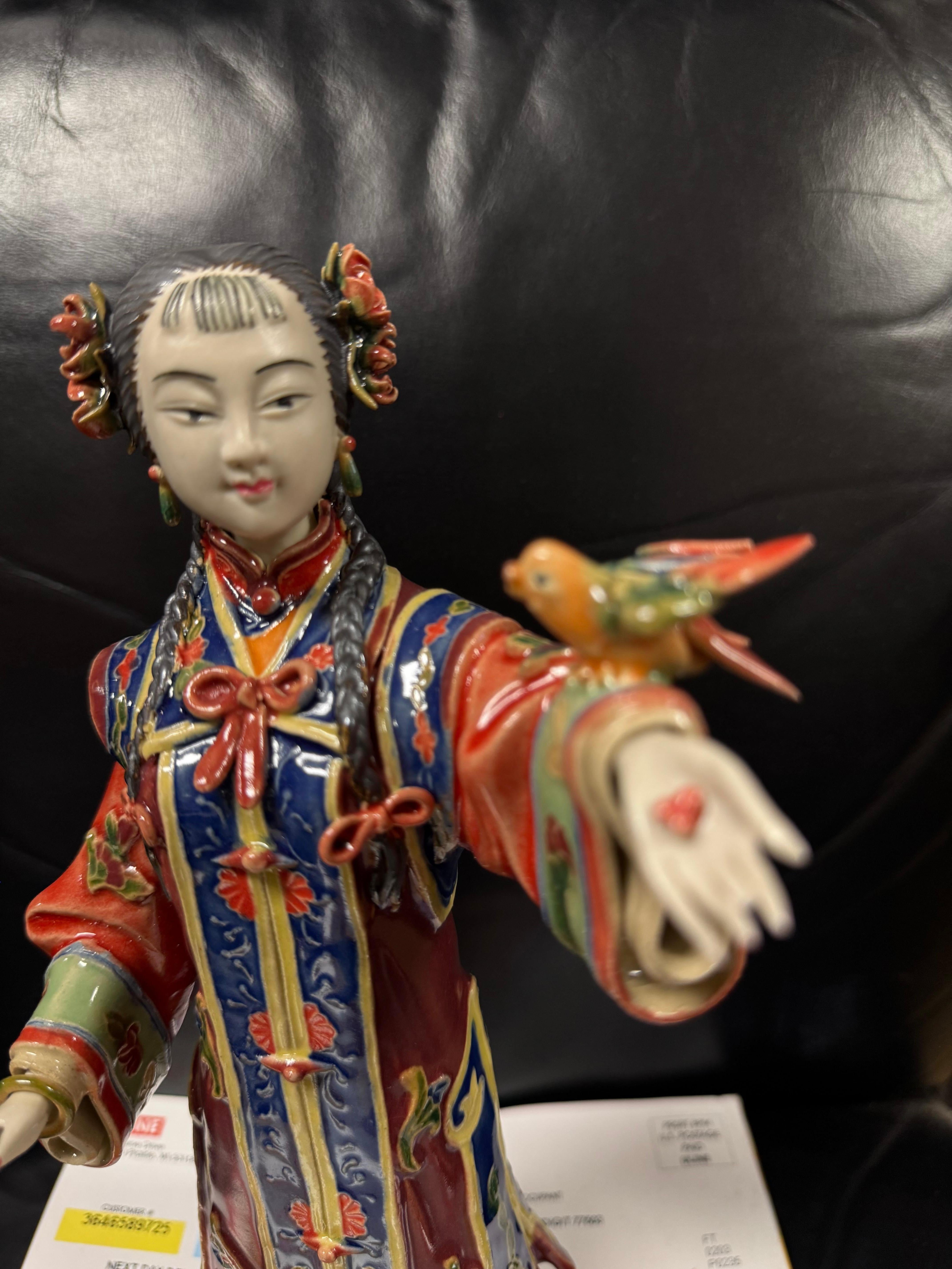 Questa è una bellissima scultura di una ragazza geisha.
È vestita con un bellissimo kimono.
Cammina con l'adorabile uccello sul braccio e il fiore tra i capelli.
La sua mano destra ha un braccialetto bangle.