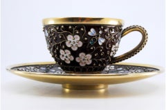 Enameled silver cup and saucer with floral motifs and gold interior