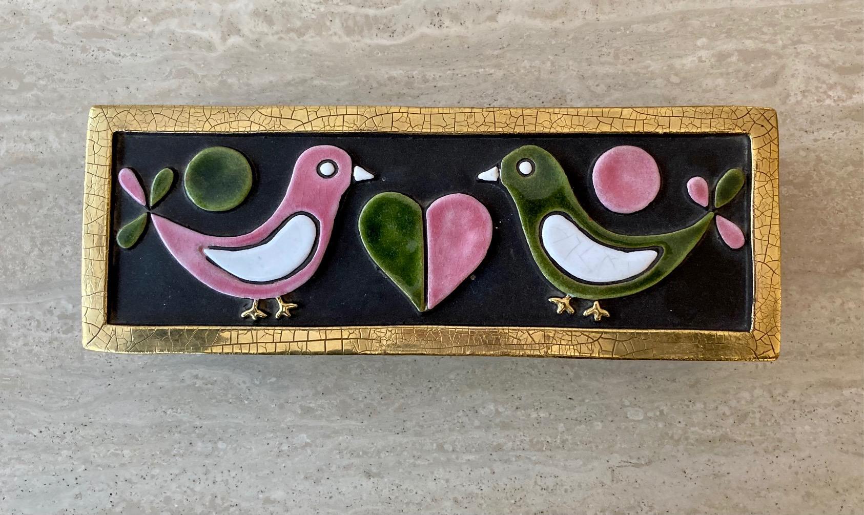An enameled ceramic top on a wooden box sporting 2 doves facing each other and a heart in the middle.
 Enameled in shades of pink, white, black and green. 
Crackled gold edges. 

Original green felt at the back of the box and of the top.

Mithé