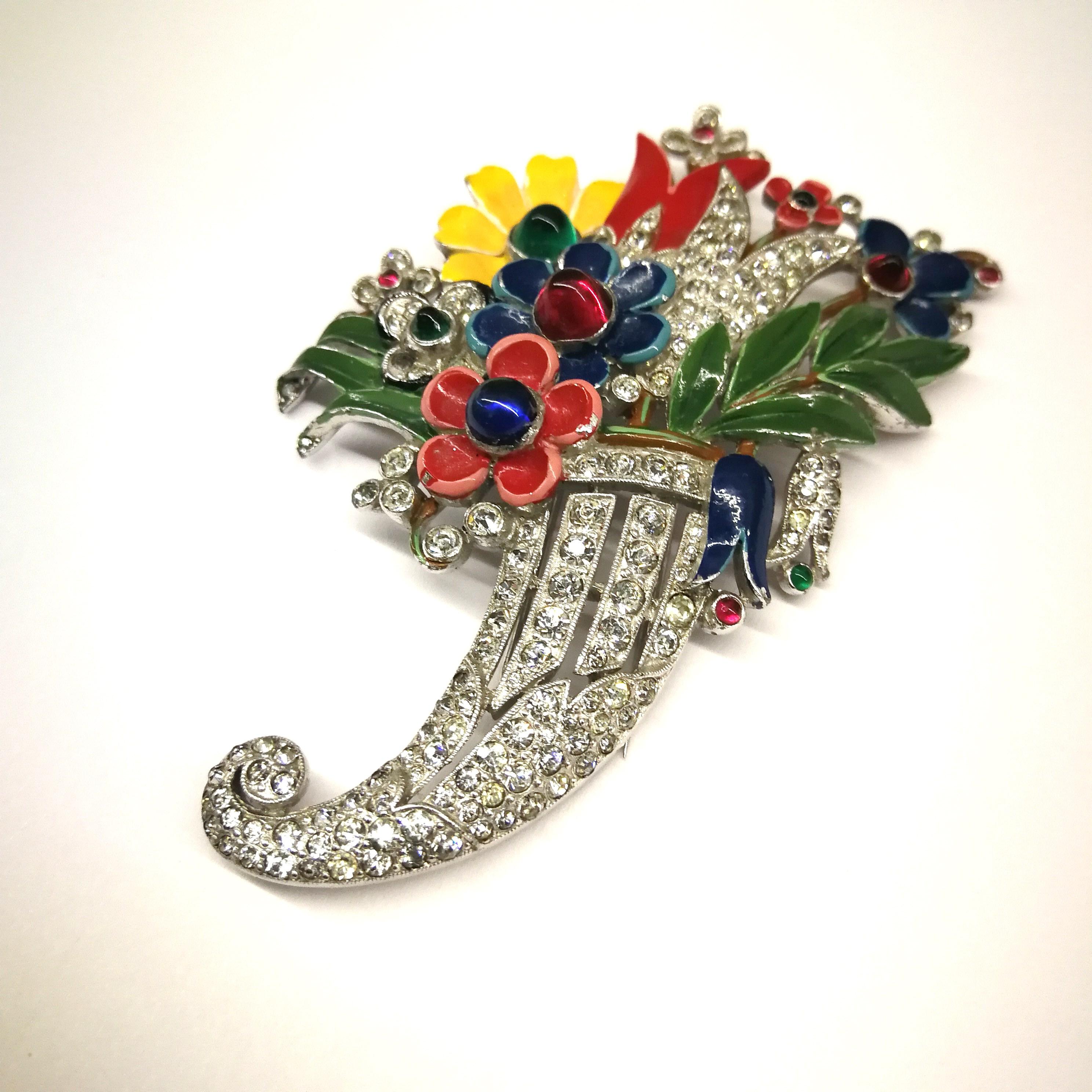 A rare and elegant enamelled brooch, from the 1930s, designed by Alfred Philippe for Trifari, in the form of an overflowing cornucopia, with flowers and leaves in beautiful fresh enamelled colours, highlighted by coloured paste cabuchons, the main