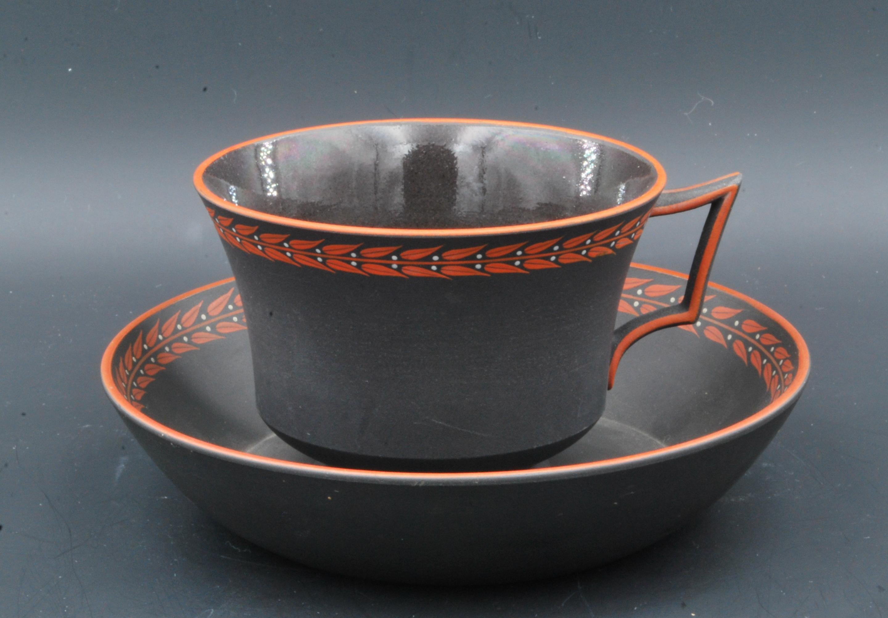 Un esempio particolarmente bello di tazza e piattino in stile neoclassico, decorato semplicemente con una linea rossa e un motivo 
