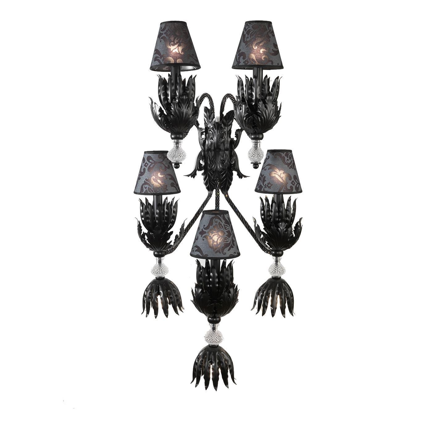 Part of the Enchanté collection, this sconce was designed by Leonardo de Carlo and will add drama and elegance to a monochromatic entryway, powder room, or living room. Its structure in hand forged iron with a black finish comprises a base