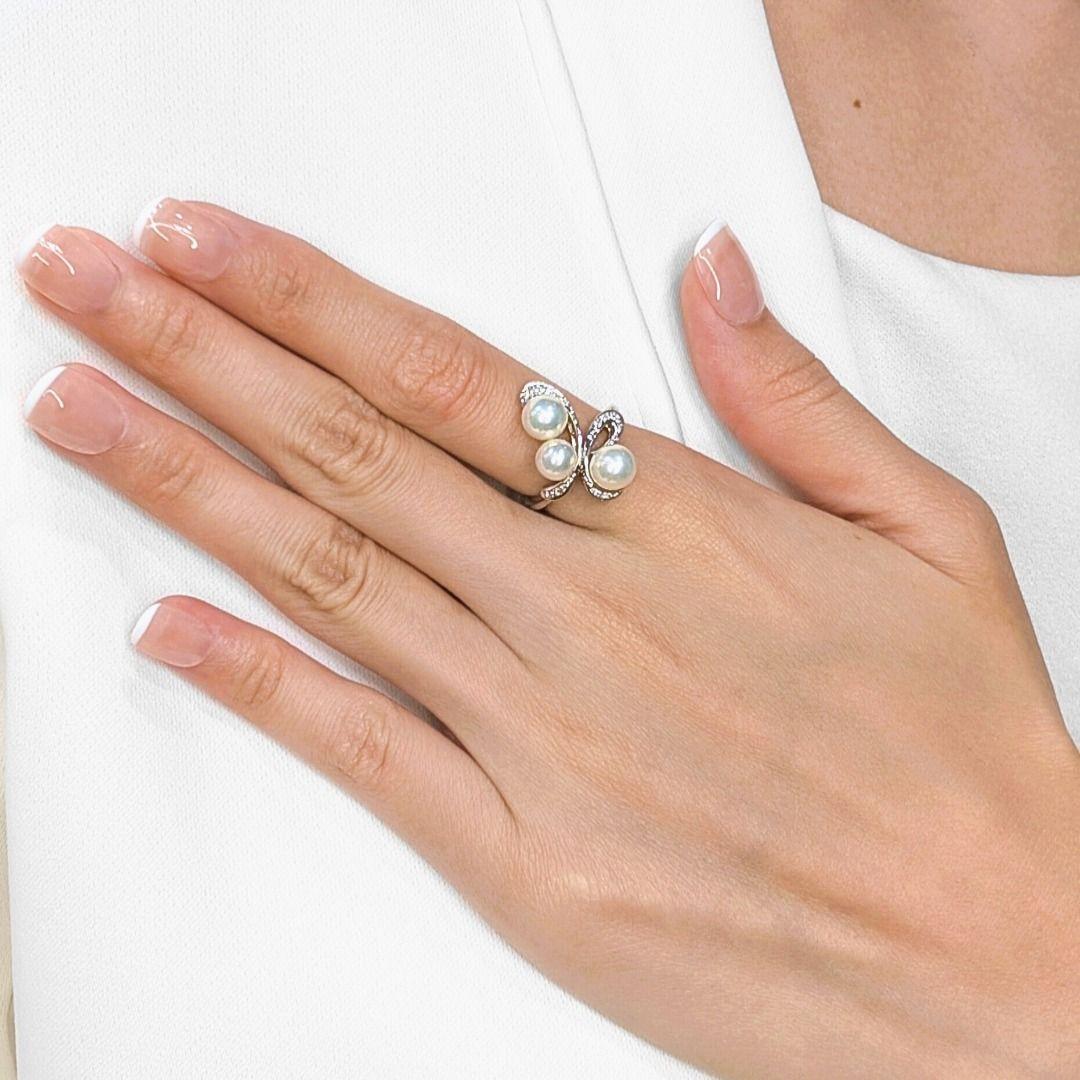 Ornez votre main de l'élégance gracieuse de cette bague, méticuleusement réalisée en or blanc 18 carats rayonnant. Cette pièce captivante présente un design délicat et fluide qui met magnifiquement en valeur trois perles d'Akoya lustrées, d'un