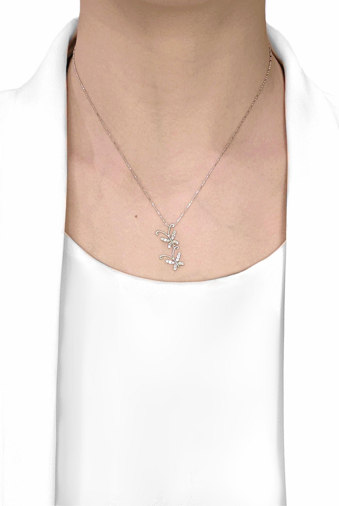 Svolazza con stile con questo nuovo, stravagante ciondolo, meticolosamente realizzato in radioso oro bianco 18 carati. Questo incantevole pezzo presenta un delicato disegno di due graziose farfalle, in bilico in un'affascinante danza. Venti diamanti