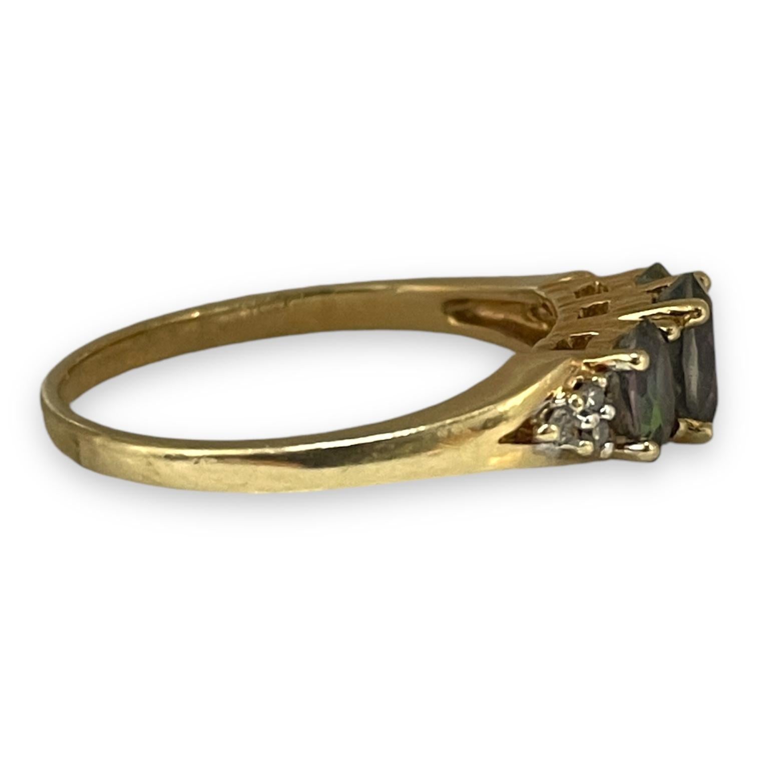 A splendid 10k yellow gold ring weighing 2.3g, this piece showcases the mesmerizing allure of three glowing alexandrite stones, flanked by delicate diamond accents. The interplay of light and color from the alexandrite adds a touch of magic, while