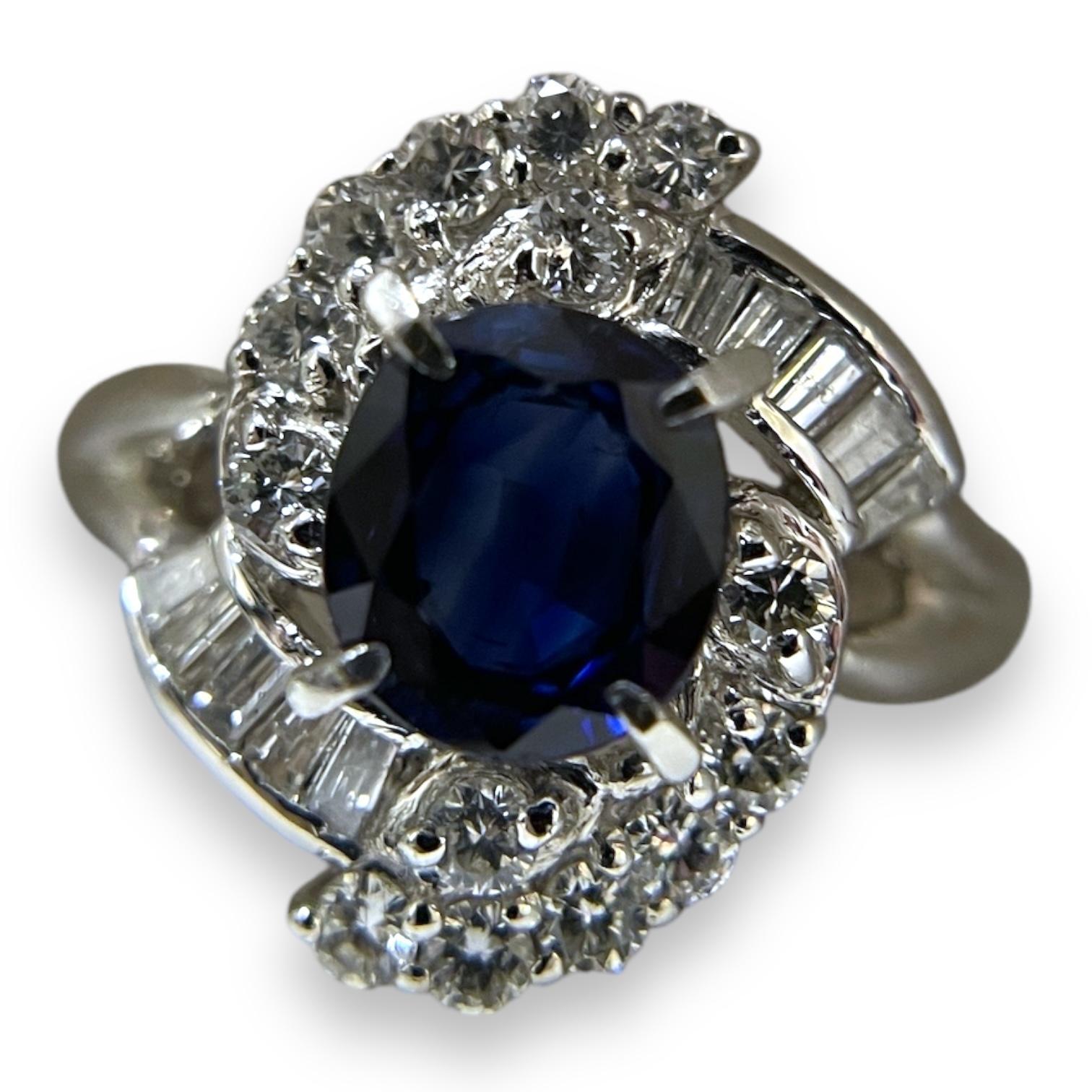 Dieser exquisite Ring zeigt einen fesselnden tiefblauen Saphir in der Mitte, umgeben von einem Heiligenschein aus funkelnden Diamanten. Die filigrane Anordnung von Diamanten im Rund- und Baguetteschliff unterstreicht den satten Farbton des Saphirs