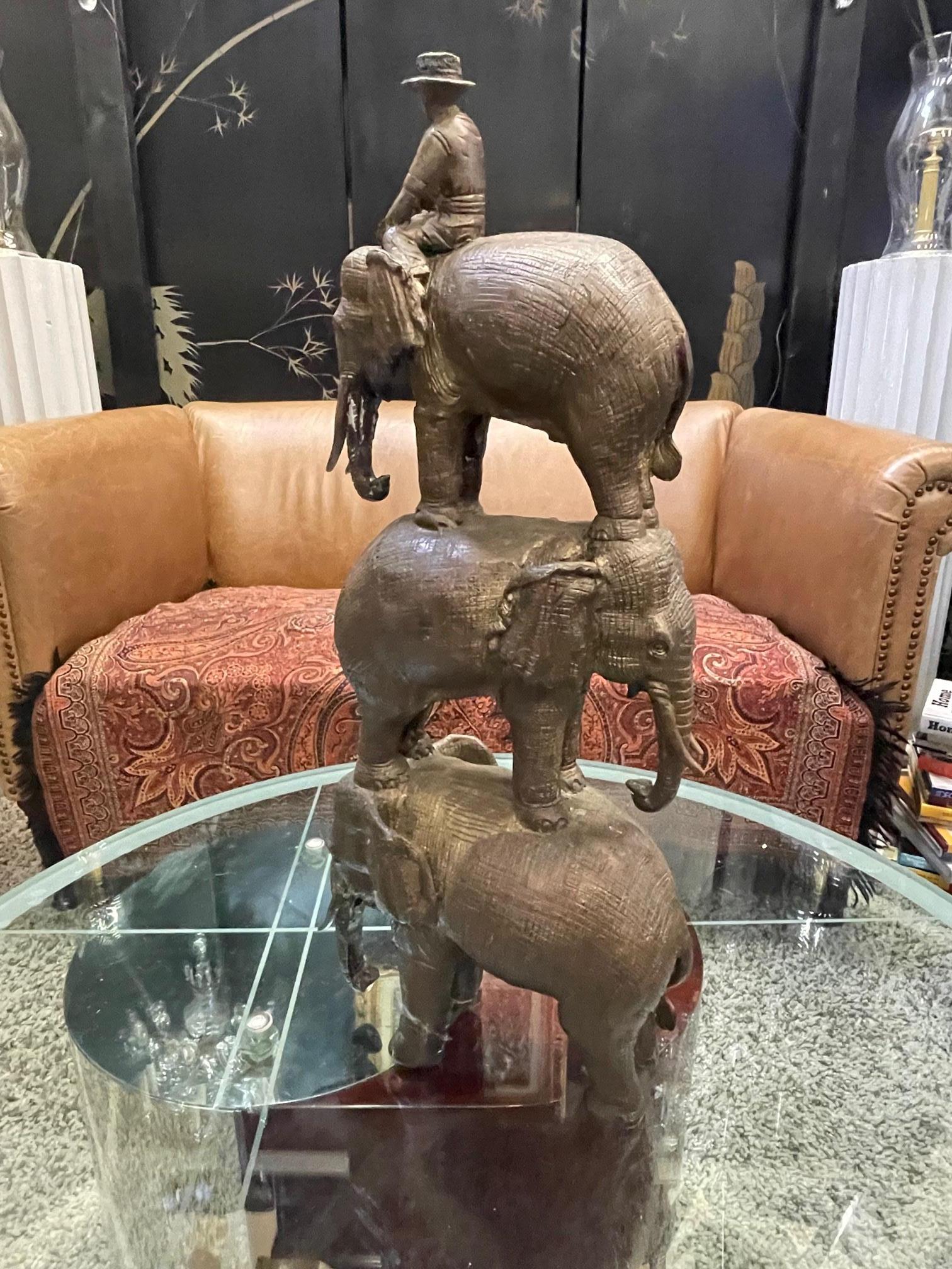 Charmante sculpture en bronze réalisée à la main représentant trois éléphants empilés les uns sur les autres, avec un cavalier seul. Non signée.