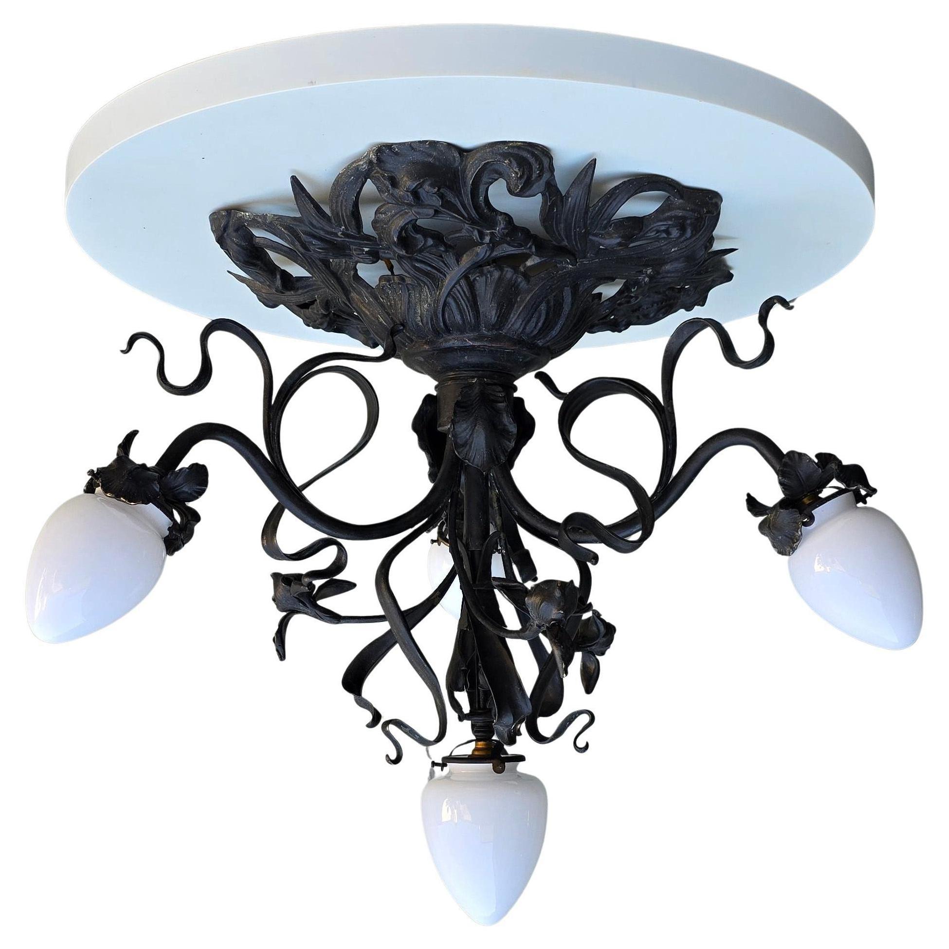 Elegant plafonnier Art Nouveau de France. En métal peint en noir avec quatre abat-jours en verre opalin blanc. Un bel exemple du style Art nouveau avec ses lignes fluides et ses formes organiques.

Ce magnifique plafonnier Art nouveau attire tous