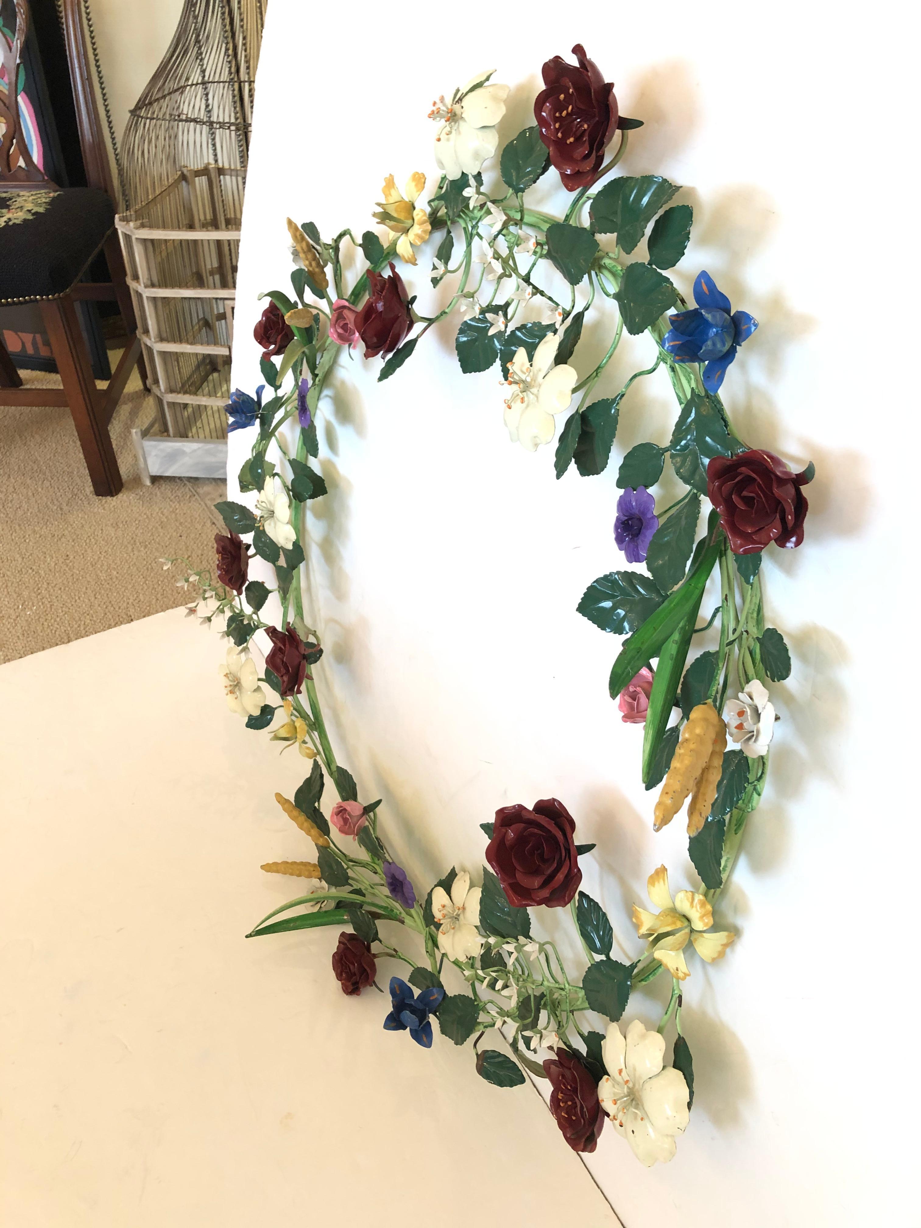 A rare refreshing large vintage iron and tole painted wreath wall sculpture having a whimsical arrangement of tole flowers as lively as Spring.