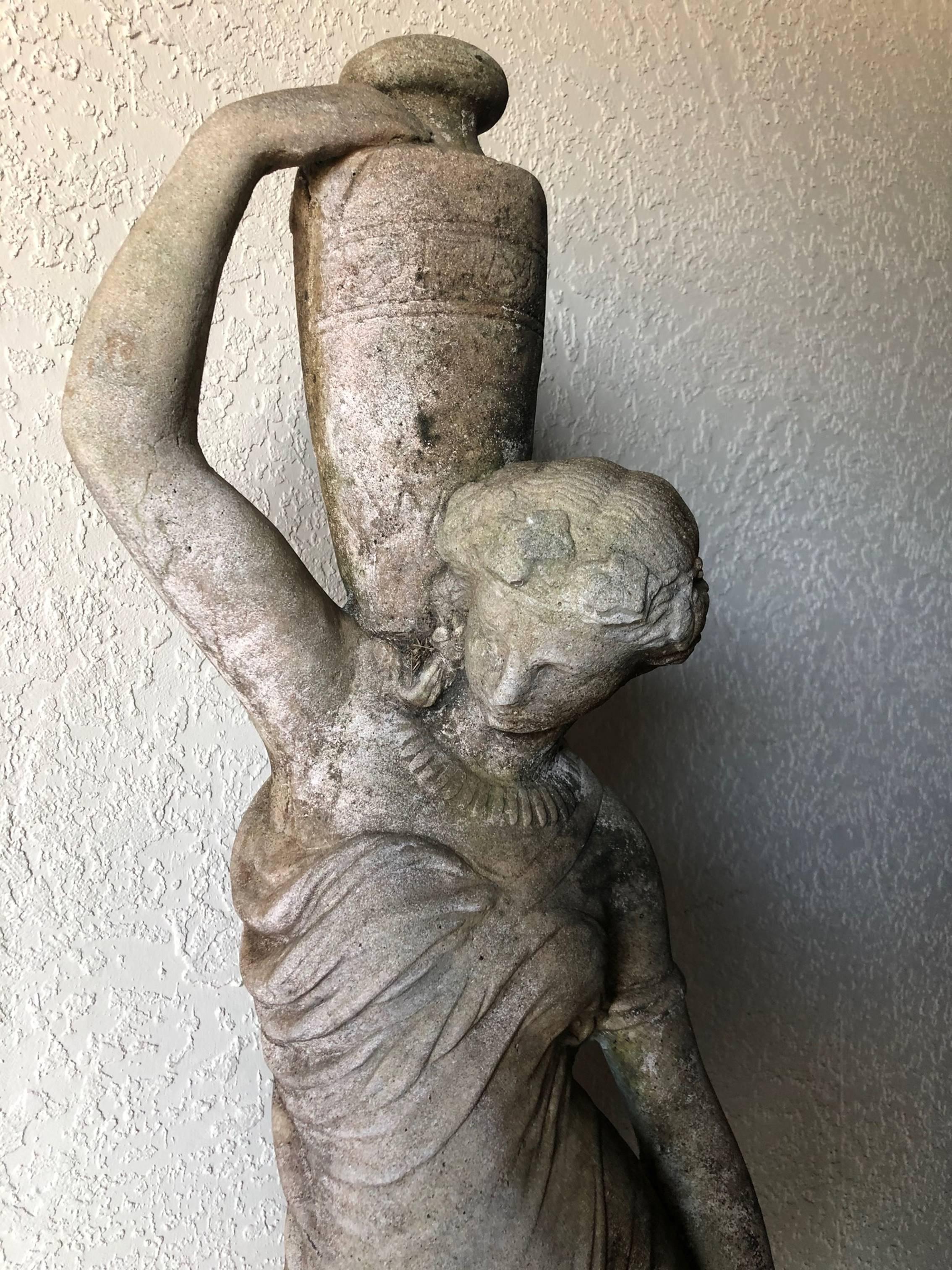 Beautiful refined neoclassical garden figural statue of a woman holding an urn. Main material is stone mixed with gravel and cement. This romantic and majestic statue was at one time a fountain (and can still be if desired). The stone shows sign of