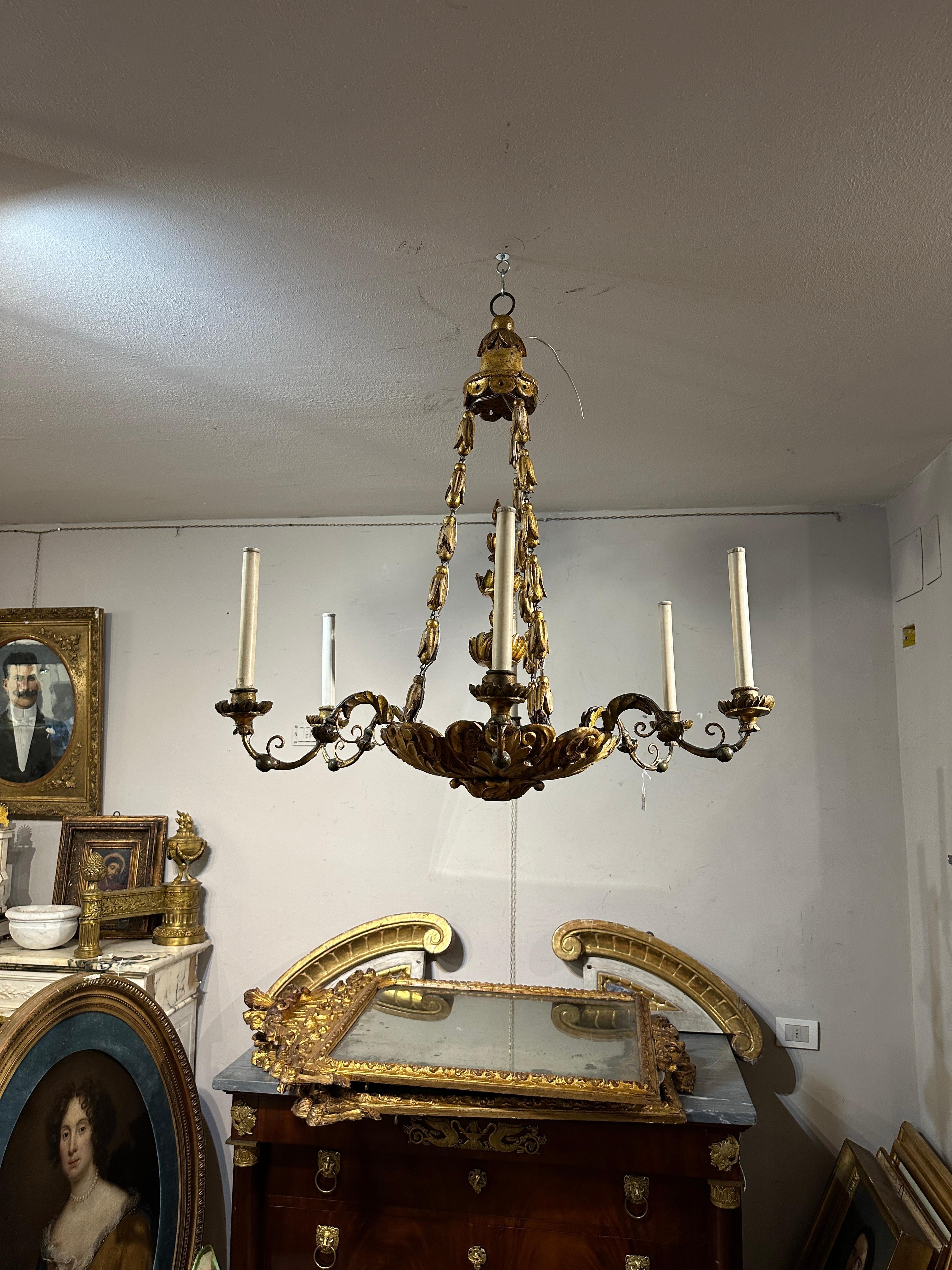 The carved wooden chandelier, produced in late 18th century Vienna, is an excellent representation of the craftsmanship of that era. Its umbrella shape, decorated with floral carvings, gives it a classic elegance, while the pure gold gilding adds a
