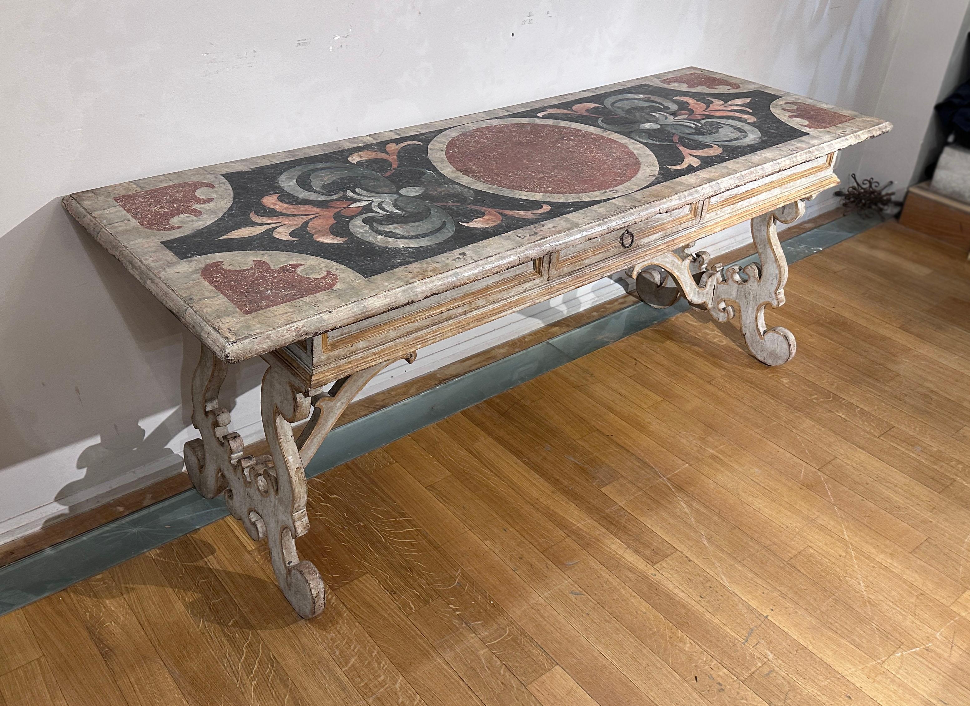 Elegant table made around the end of the 17th century by artisans from the Marche region in painted fir wood. Its design is characterized by a rectangular top, supported by lyre-shaped legs. The pictorial decorations of the top feature motifs that