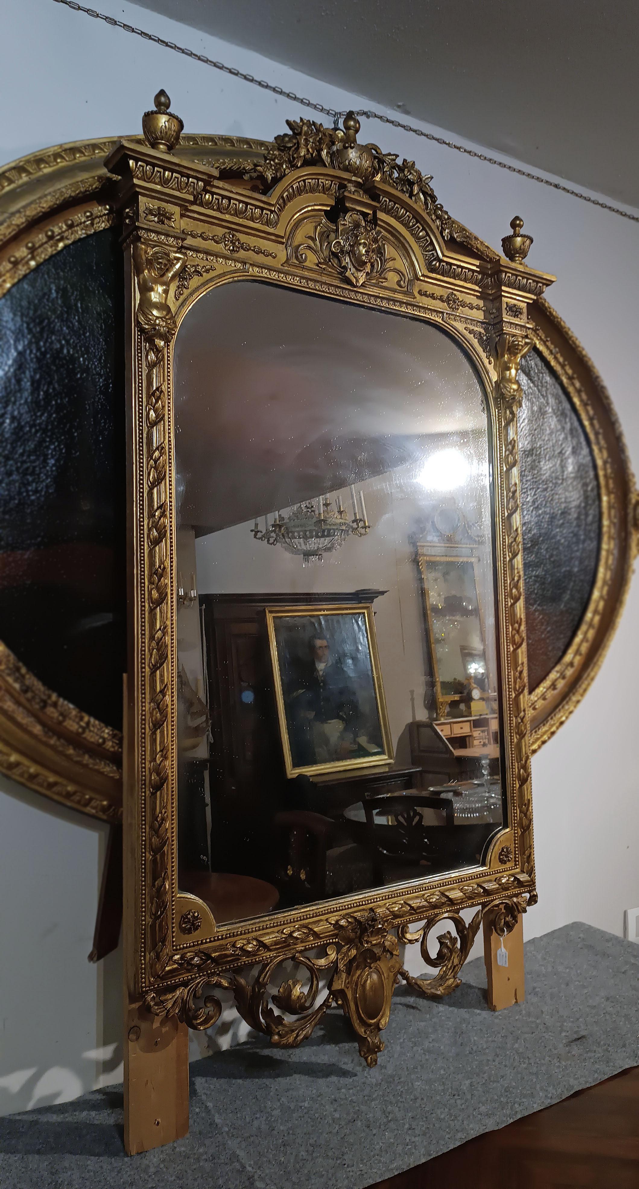 Beautiful and elegant mirror in carved wood and gilded tablet with pure gold leaf. The frame is decorated with elegant vegetal motifs on the sides and in the lower part, while in the upper part it has an architectural bracket-like termination