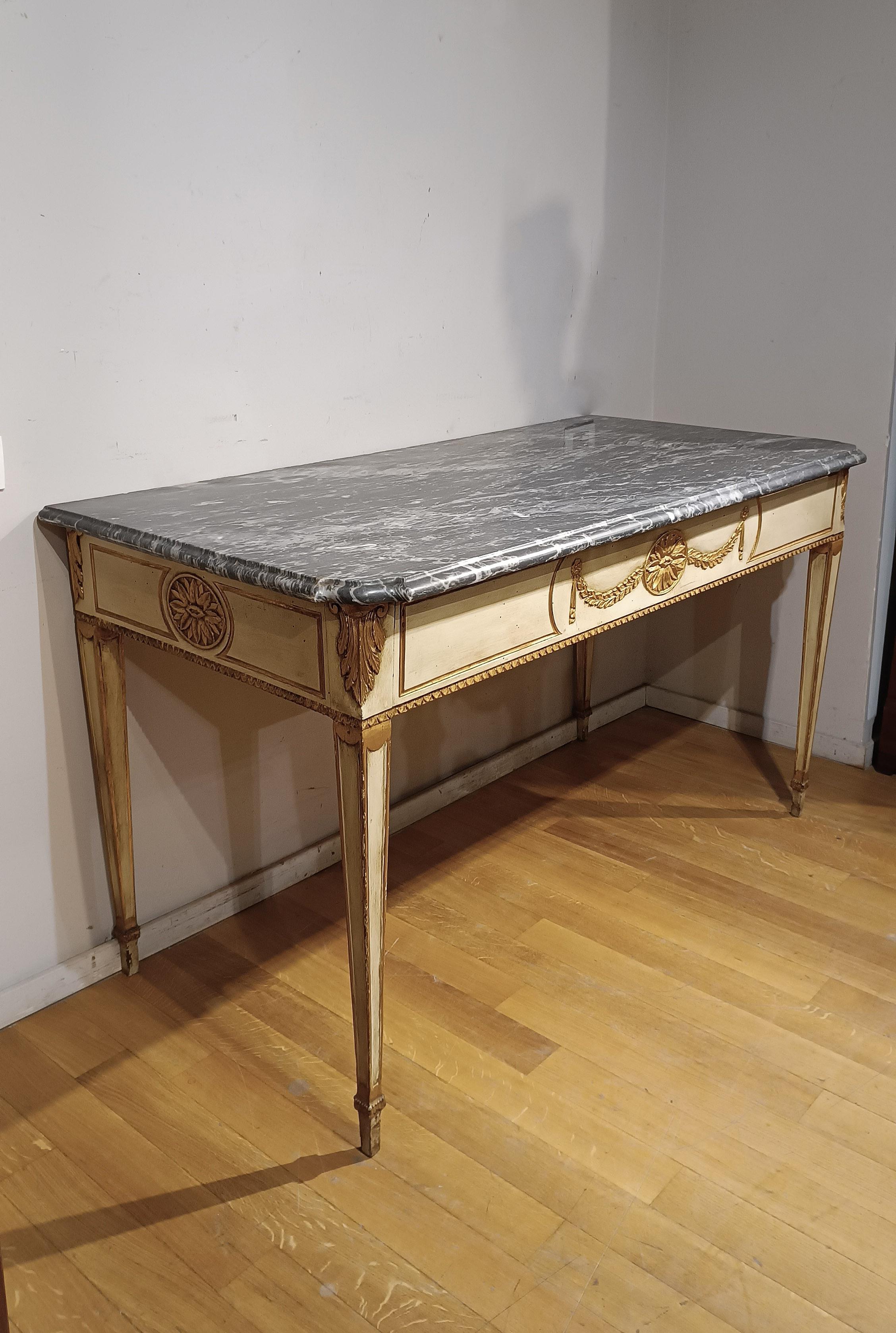 Elegant neoclassical console table in poplar wood painted with a delicate pastel light green color. The refined details, such as the carved and gilded finishes in pure gold, give the piece of furniture a classicizing taste, typical of the