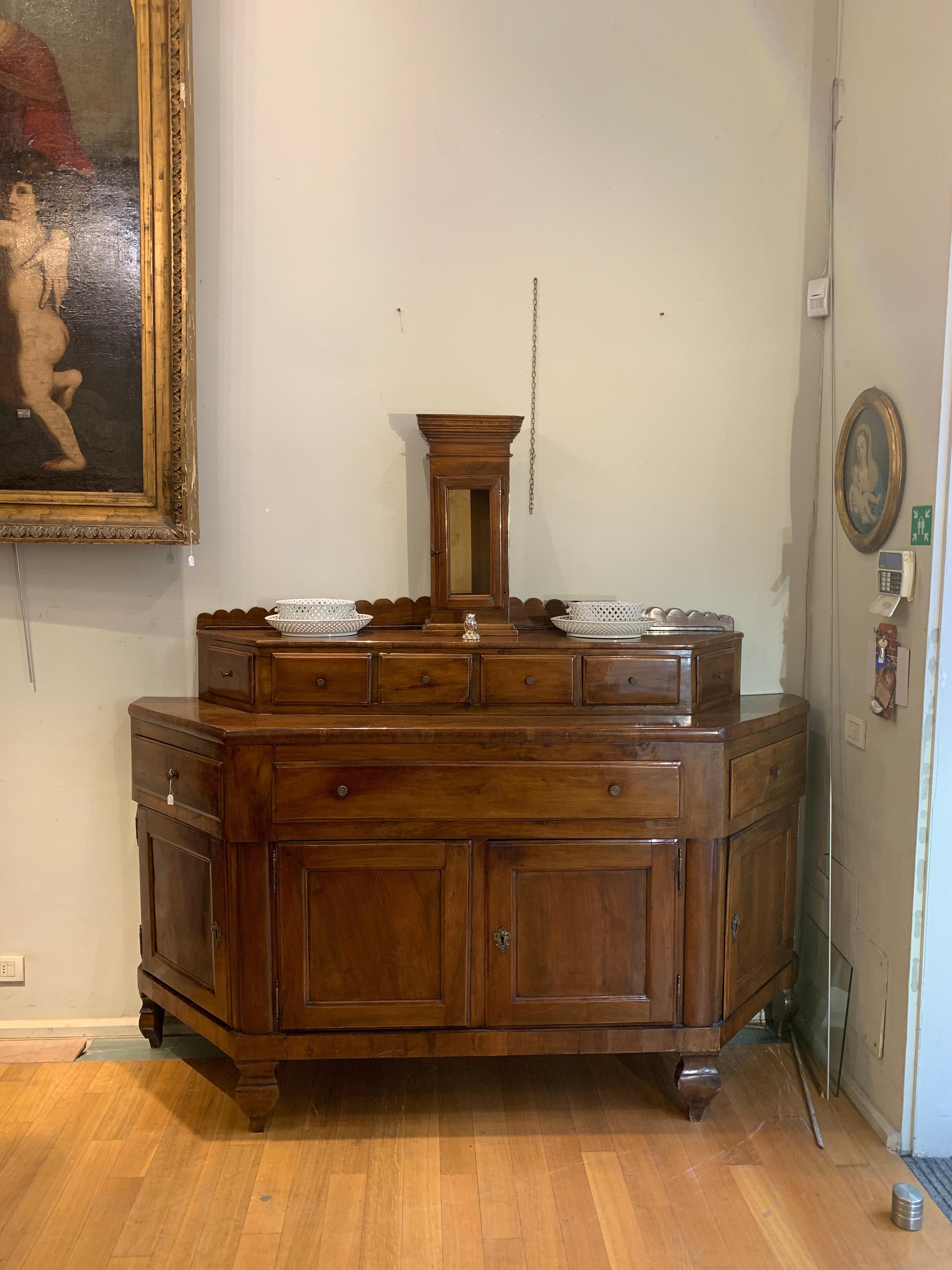 Splendid and rare solid walnut sideboard characterized by an original and functional design. This piece of furniture has a notched structure, enriched by four doors and three drawers in the upper part. Furthermore, it is embellished with an elegant