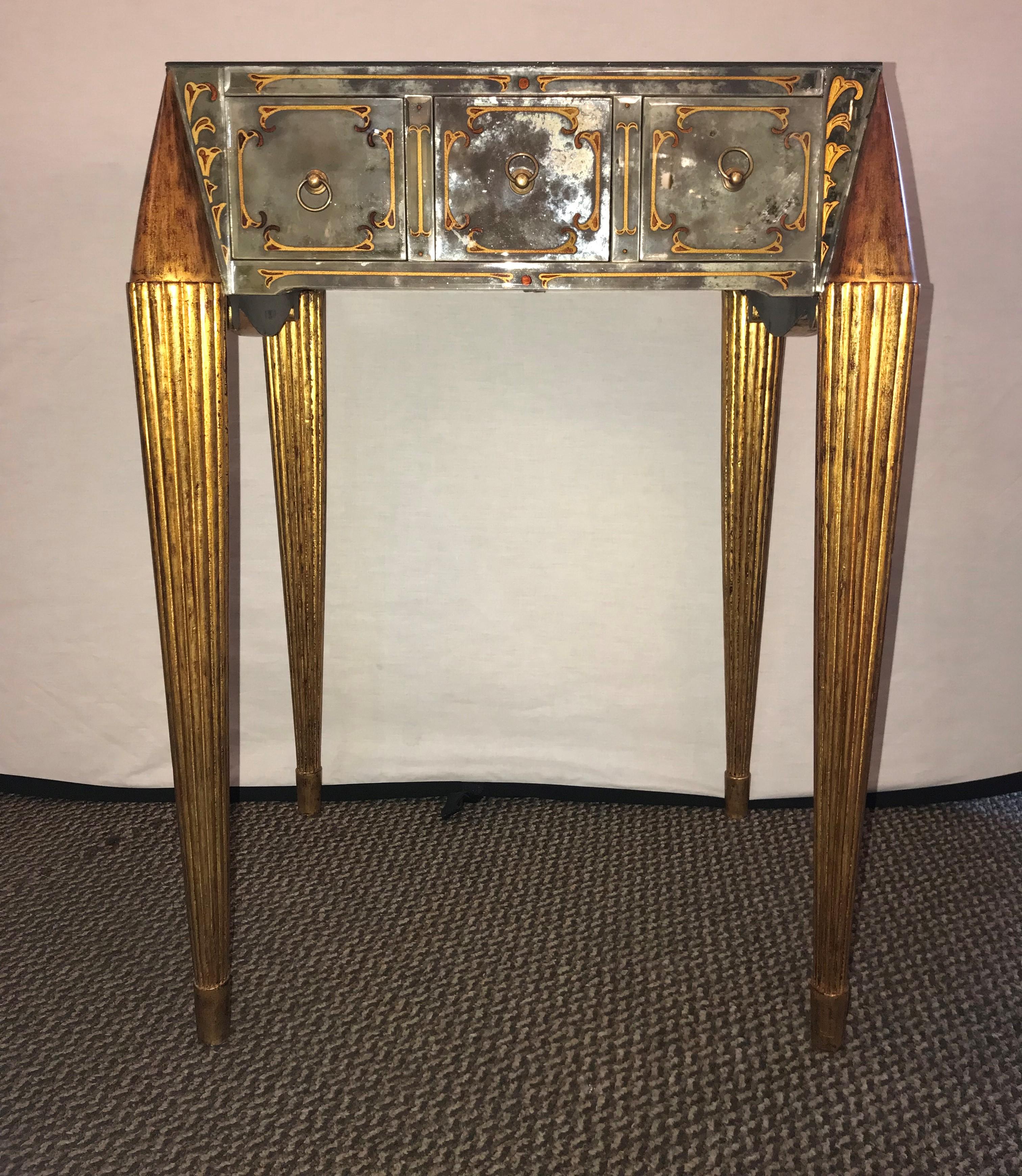 An end table with gilt legs and églomisé designed mirrored top and sides. Having fine gilt legs supporting an upper case of églomiséd mirrored glass with one drawer. There is a small two inch damage to the top that is really not very noticeable. We