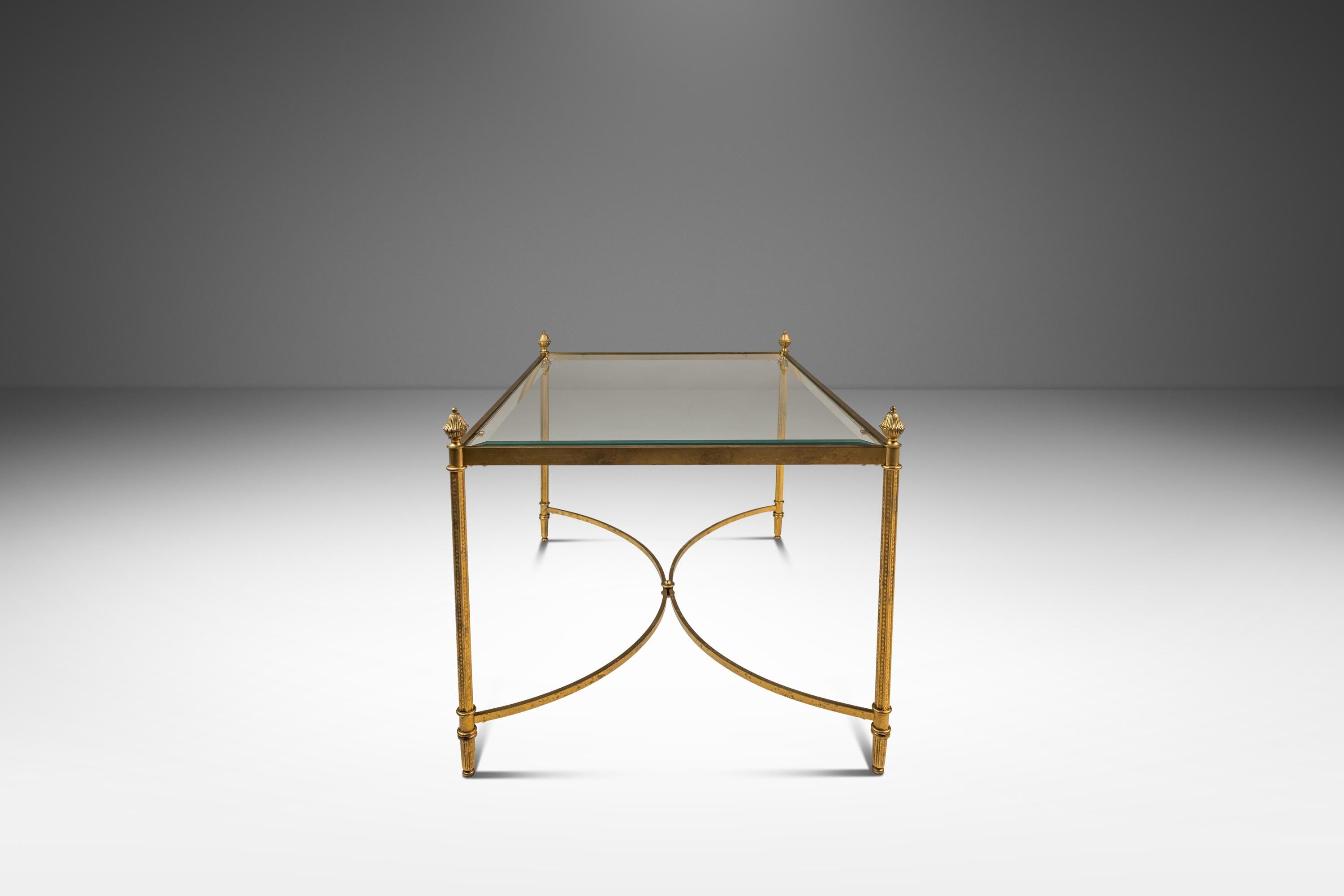 Questo sofisticato tavolino da salotto o da caffè in stile Mid-Century Modern Hollywood Regency, ispirato agli opulenti design della Maison Bagues, affascina per la sua eleganza anni '70 circa. Realizzato con una finitura patinata in ottone, il