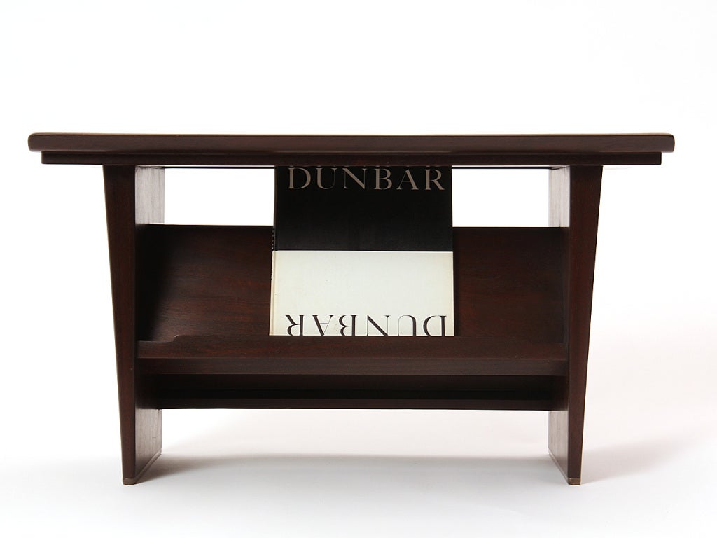 A Mid-Century Modern dark walnut end table designed by Edward Wormley. Table features angled shelves for books or magazines, and tapered slab legs finished with solid brass runners. Made by Dunbar in the USA, circa 1950s.
  