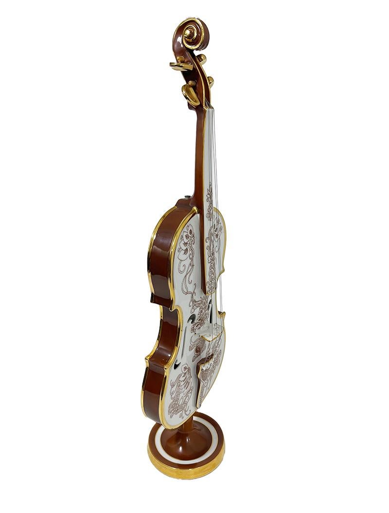 Endre László Szász for hollohaza porcelain violin, Hungary 1979-1980.

A Hungarian porcelain violin on a round stand with a brown painted scene on the front of grapes and vines and on the back painted a female head with bird, sun, surrounded by
