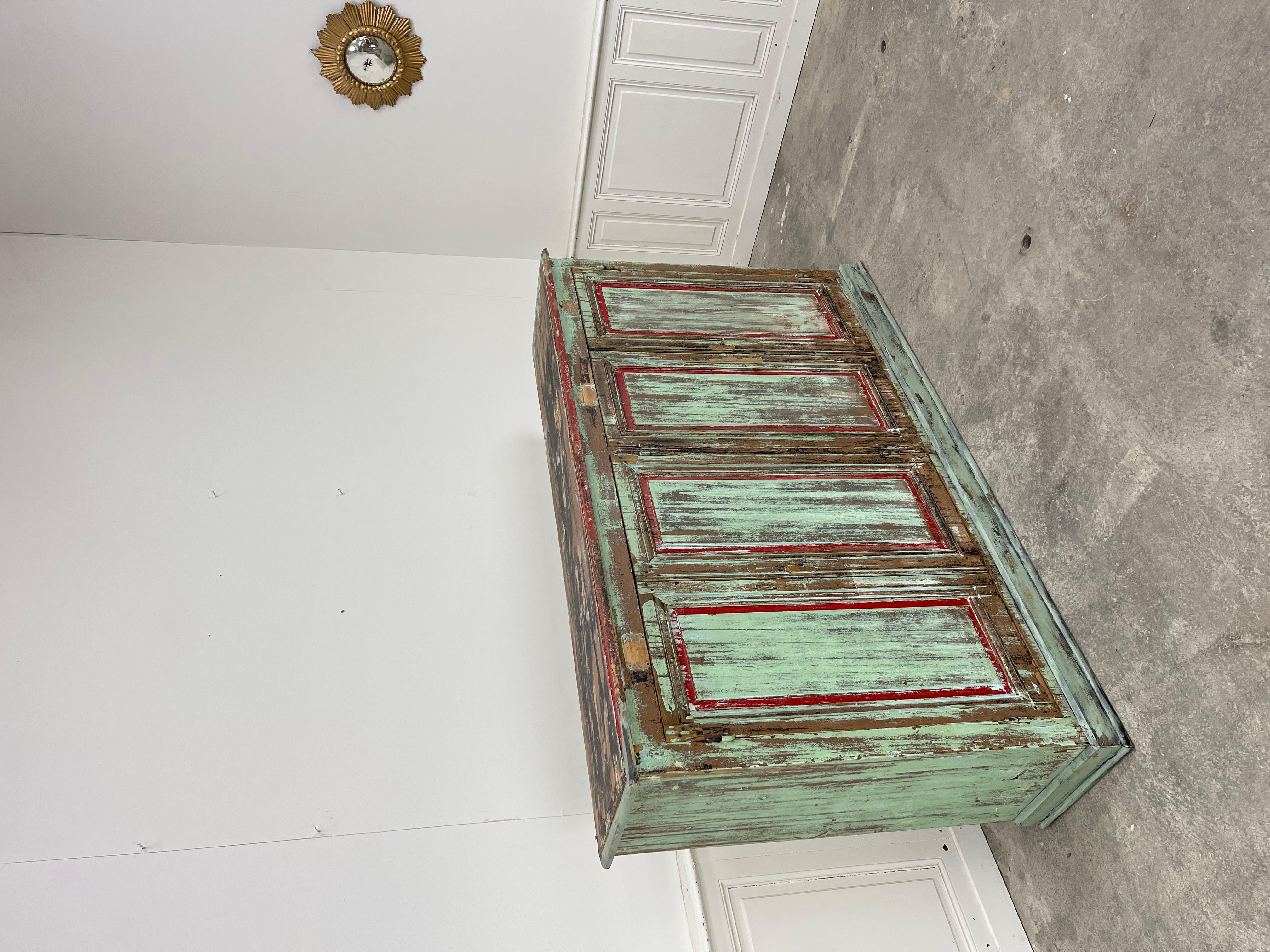 Una bella enfilade d'atelier en pin avec 4 portes, datata degli anni 1920.  La sua patina di tonalità gris, rouges e vert d'eau dona a questo mobile di mestiere un grande valore aggiunto.
Questa enfilade vintage con una grande capacità di