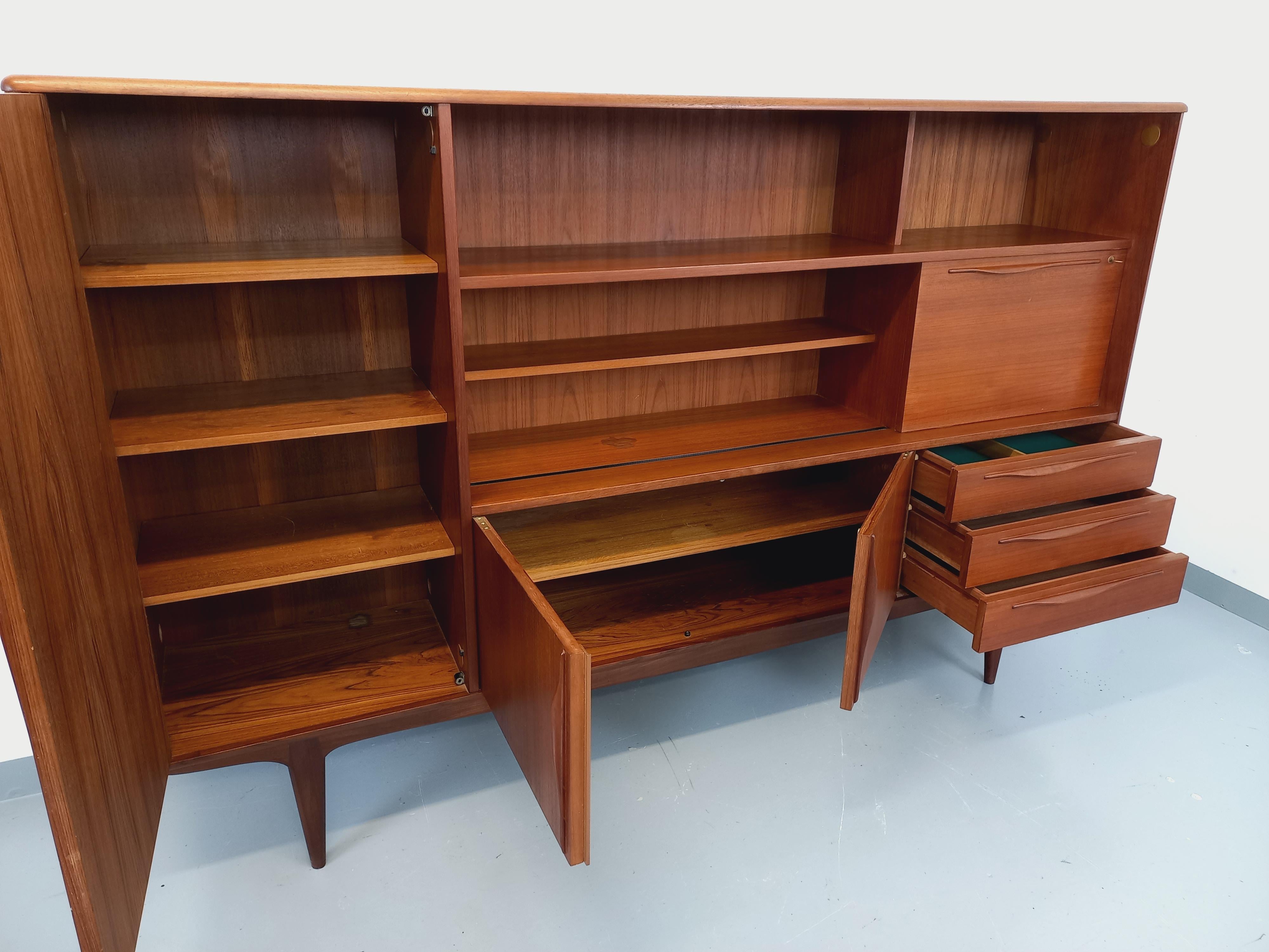 Enfilade haute scandinave des années 50 60 en teck, très beau travail des poignées et des pieds et belles finitions des angles et arêtes. Très bon état général avec des signes du temps qui passe, dont une tache dans une des niches et quelques