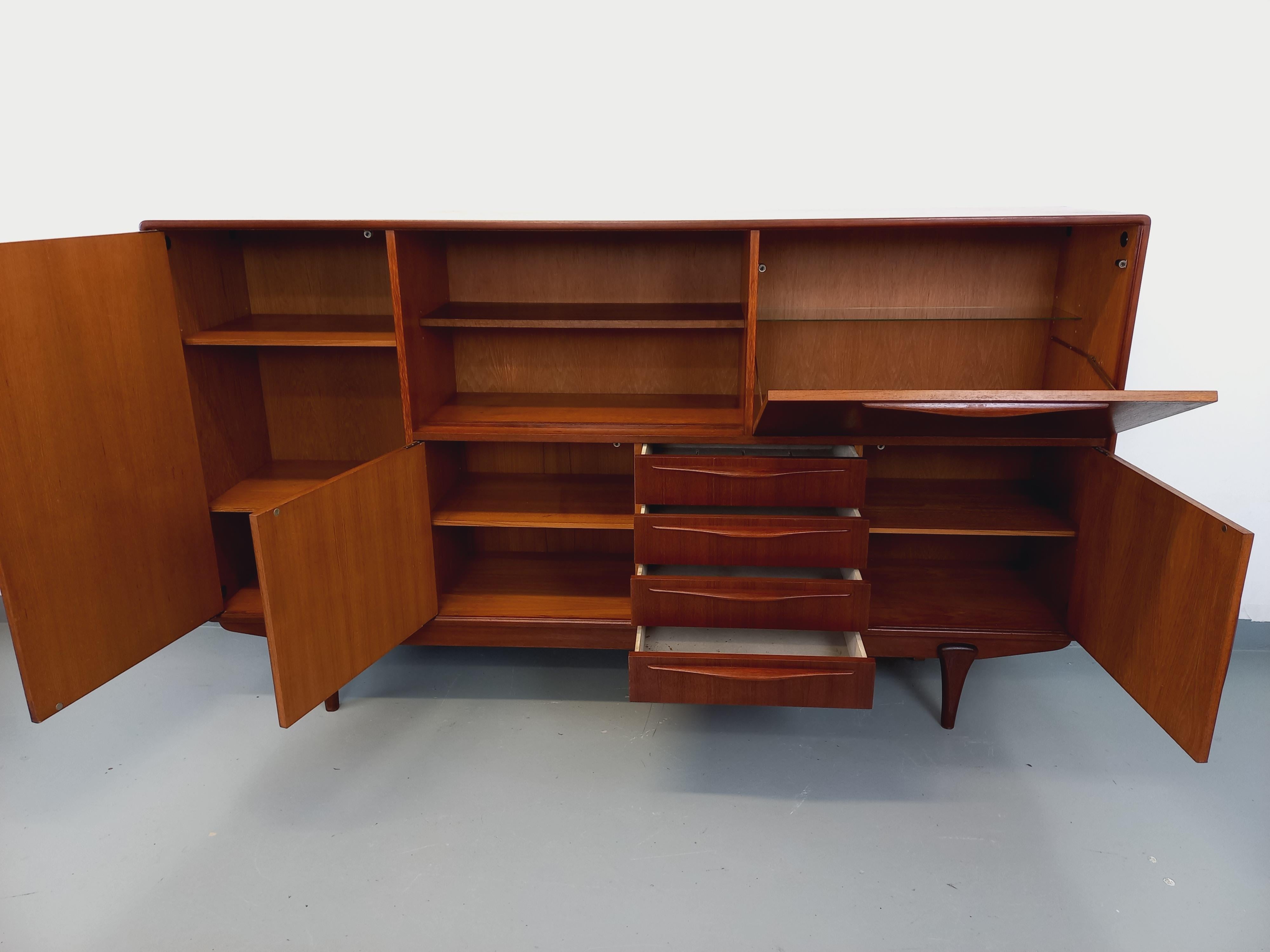 Enfilade haute scandinave des années 50 60 en teck, très beau travail des poignées et des pieds et belles finitions des angles et arêtes. Très bon état général avec quelques signes du temps qui passe. Beaucoup de rangements : étagères, partie bar,