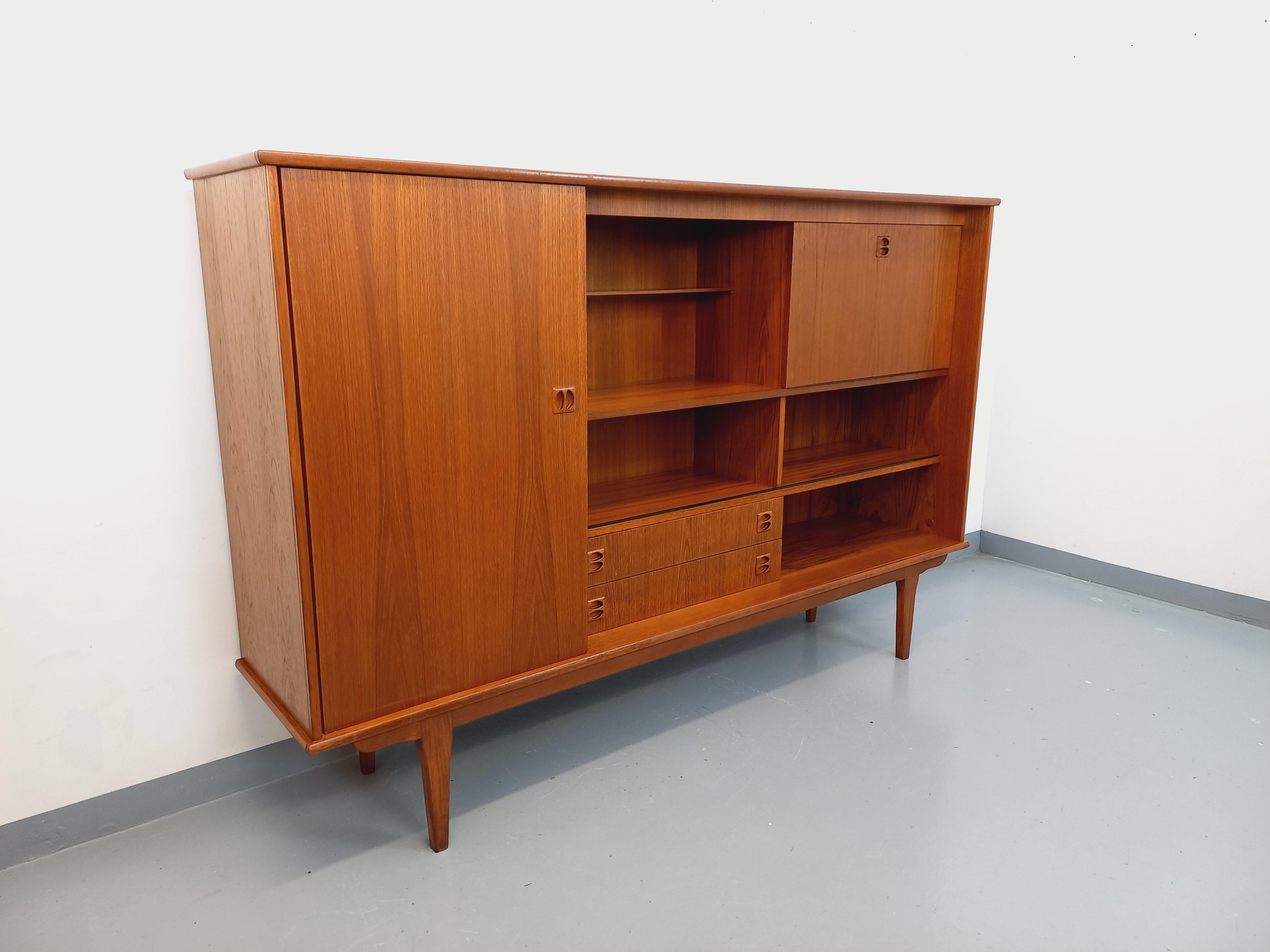 Enfilade haute vintage style scandinave des années 60, en teck, jolis boutons de portes, pieds compas, très bon état général avec quelques signes du temps qui passe. Un gran numero di ambienti: 1 grande porta con vetrine interne, 1 parte bar con