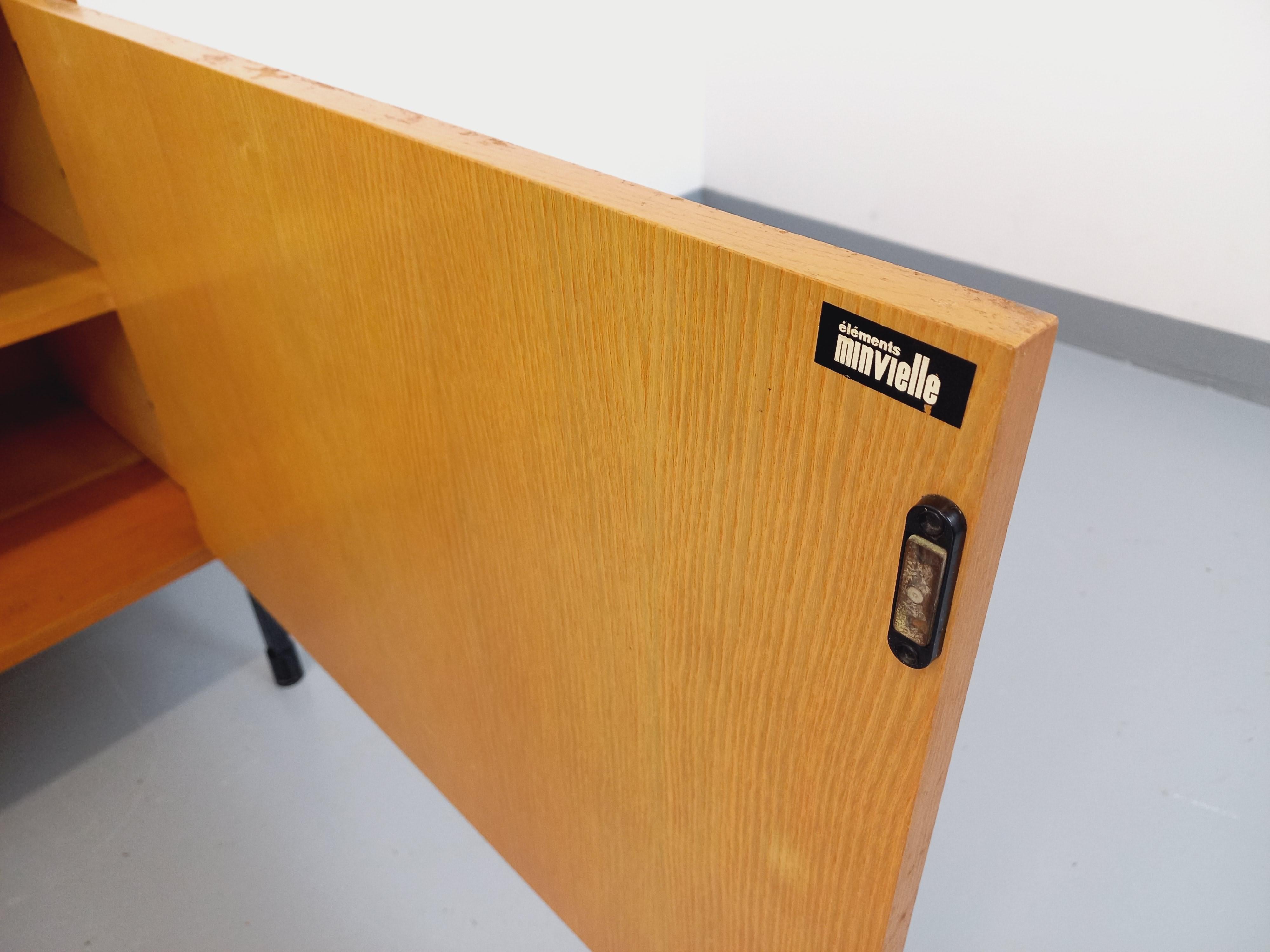 Enfilade vintage ARP Minvielle des années 60 attribuée à Pierre Guariche, Michel Mortier et Joseph-André Motte (étiquette Minvielle présente), de style moderniste et de taille moyenne, en bois de frêne, pieds en métal noir, 1 porte avec bouton en