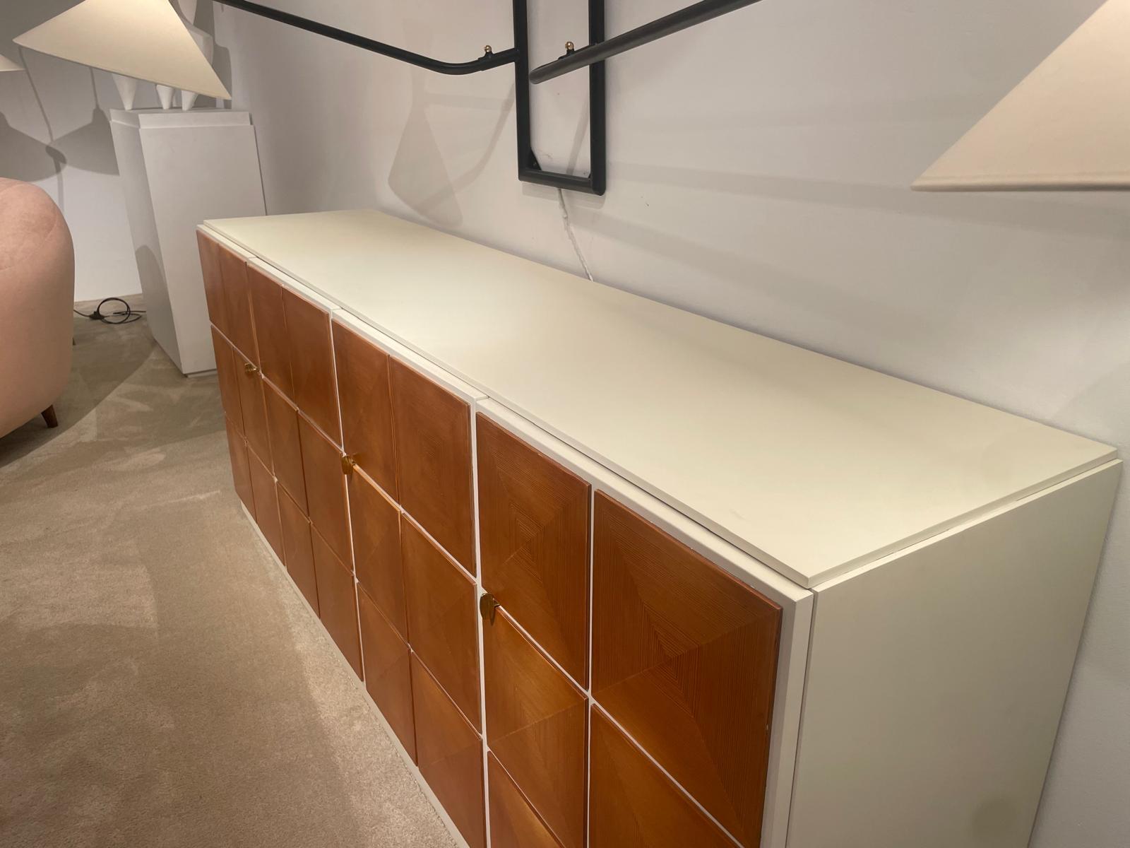 This exceptional Scandinavian sideboard captures the essence of mid-century modern refinement, where functionality and aesthetics merge seamlessly. The façade is composed of a striking sequence of square panels in warm veneered wood, each