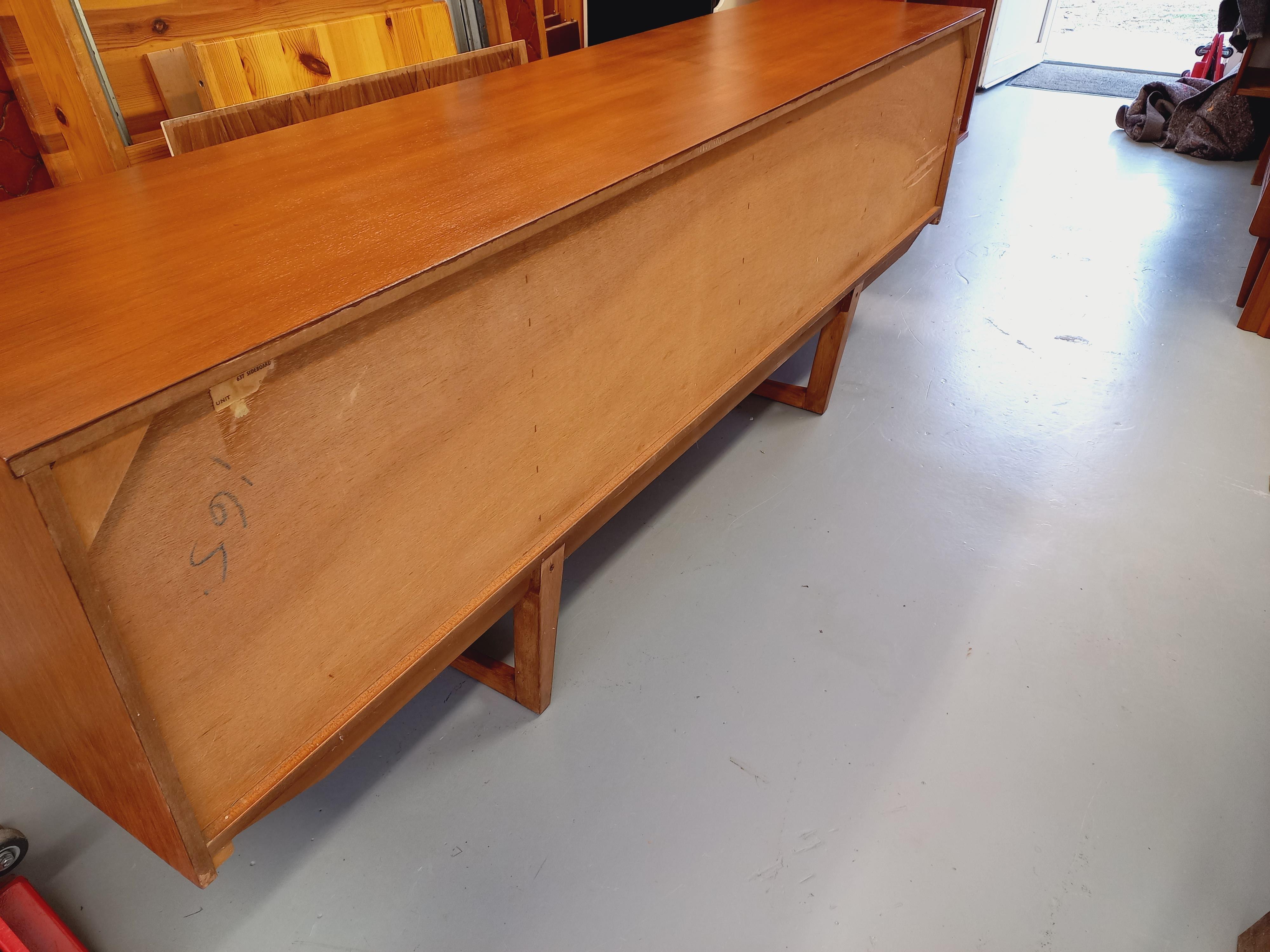 Enfilade basse vintage style scandinave des années 60, en teck. Atypique avec ses pieds traîneaux, ses poignées originales et ses insertions bois sur les portes. Beaucoup de rangements : 2 portes avec étagères, 1 porte abattante avec partie bar et