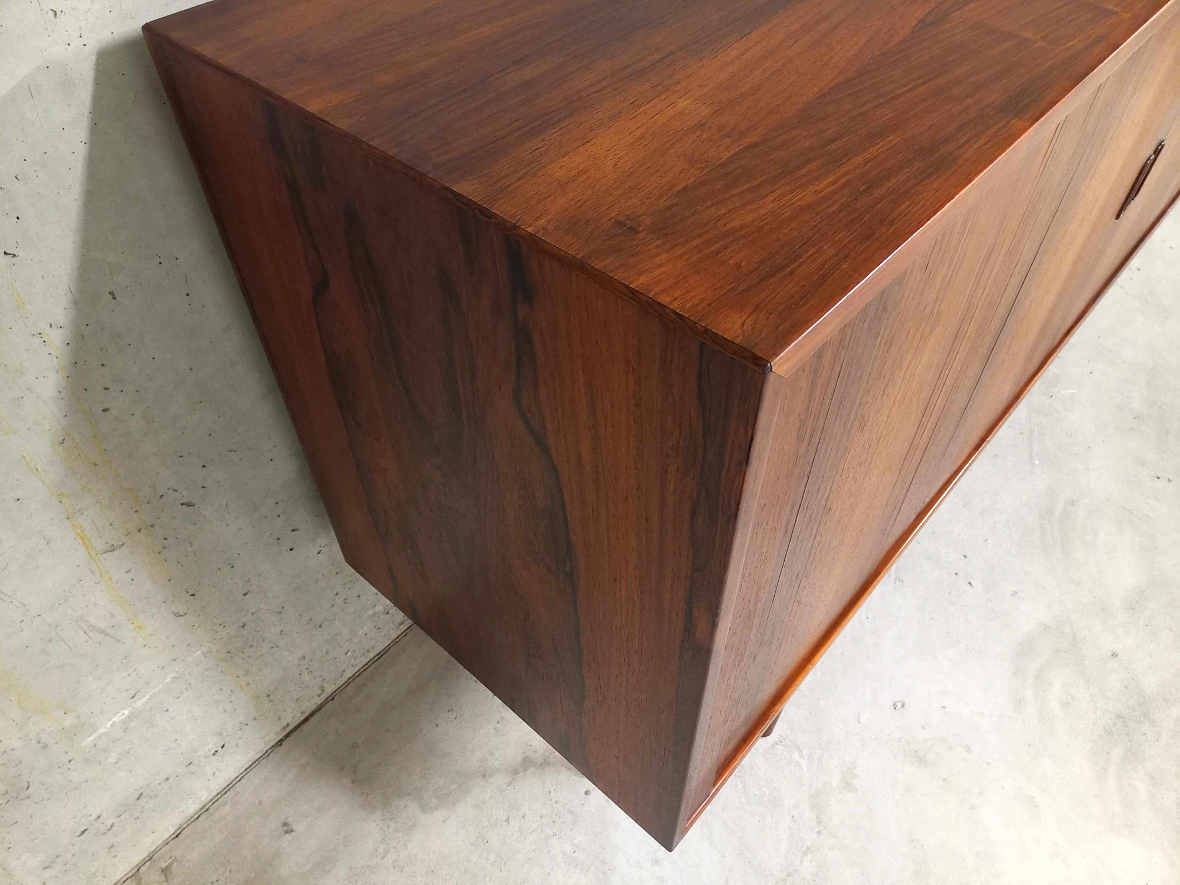 Profilo basso vintage scandinavo degli anni '60, in palissandro, attribuito al designer danese Arne Vodder, modello OS-36, fabbricazione Sibast Møbelfabrik.
Molto bello il lavoro delle porte a coulisse, chiamate anche porte a tamburo o porte a
