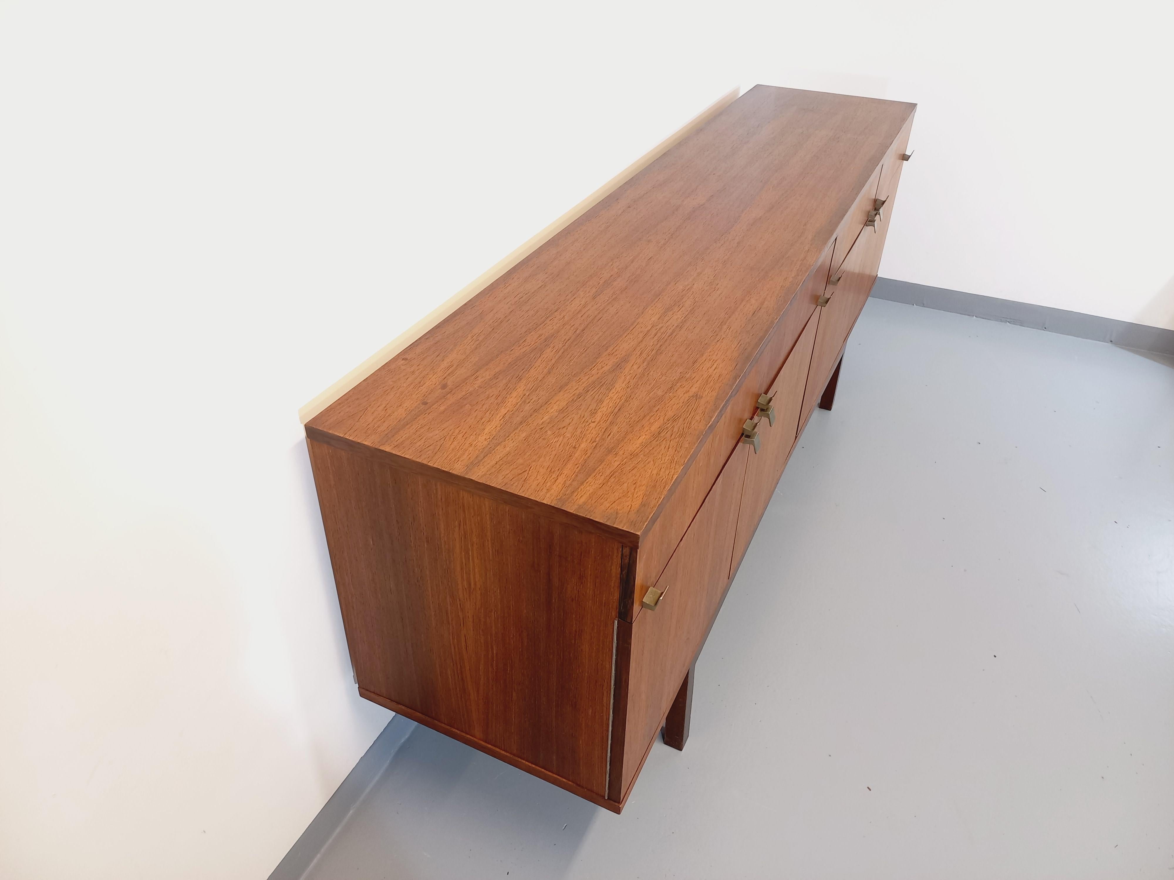 Enfilade basse vintage style scandinave des années 60, en palissandre, poignées laiton, dans le goût du designer André Monpoix. Beaucoup de rangements : 3 portes avec étagères, 4 tiroirs et 1 partie bar. Très bon état général avec quelques signes du