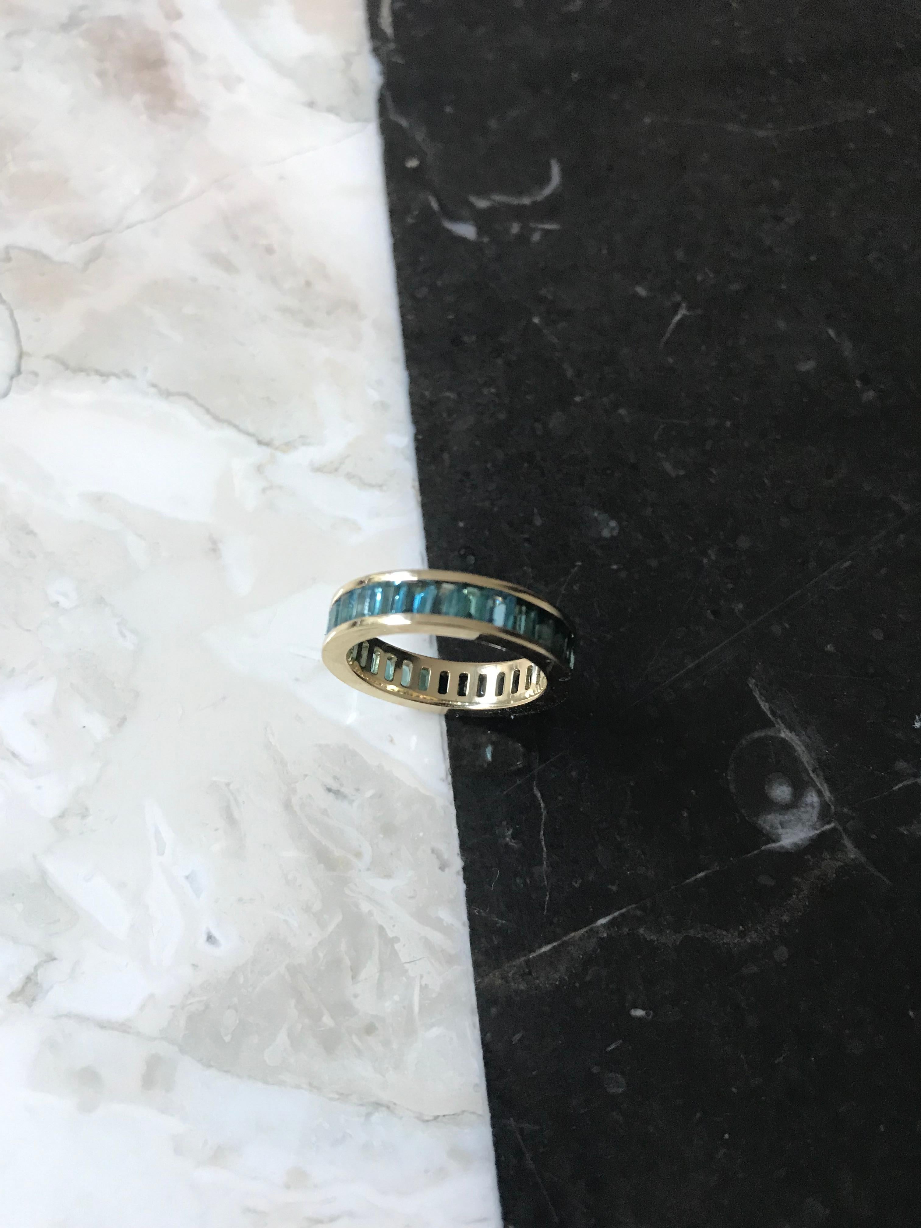 Eternity ring invisibly-set with rare blue color tourmaline with 18k yellow gold. Invisibly set all the way around. Approximate carat weight 3.2. Crafted by master craftsmen in Italy.

Fouché bespoke band rings are created according to your band