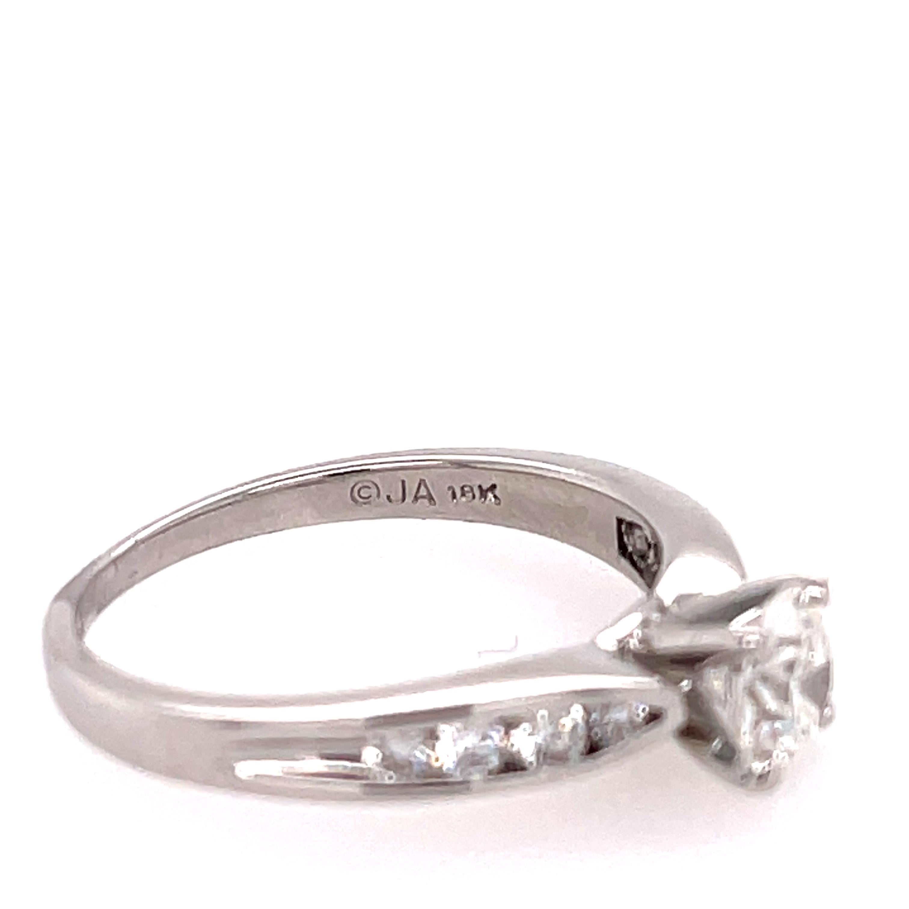 Diamond engagement ring in 18K white gold. The ring features a 0.72ct brilliant round center and 8 channel set diamonds on the side. Stamped JA 14K.  