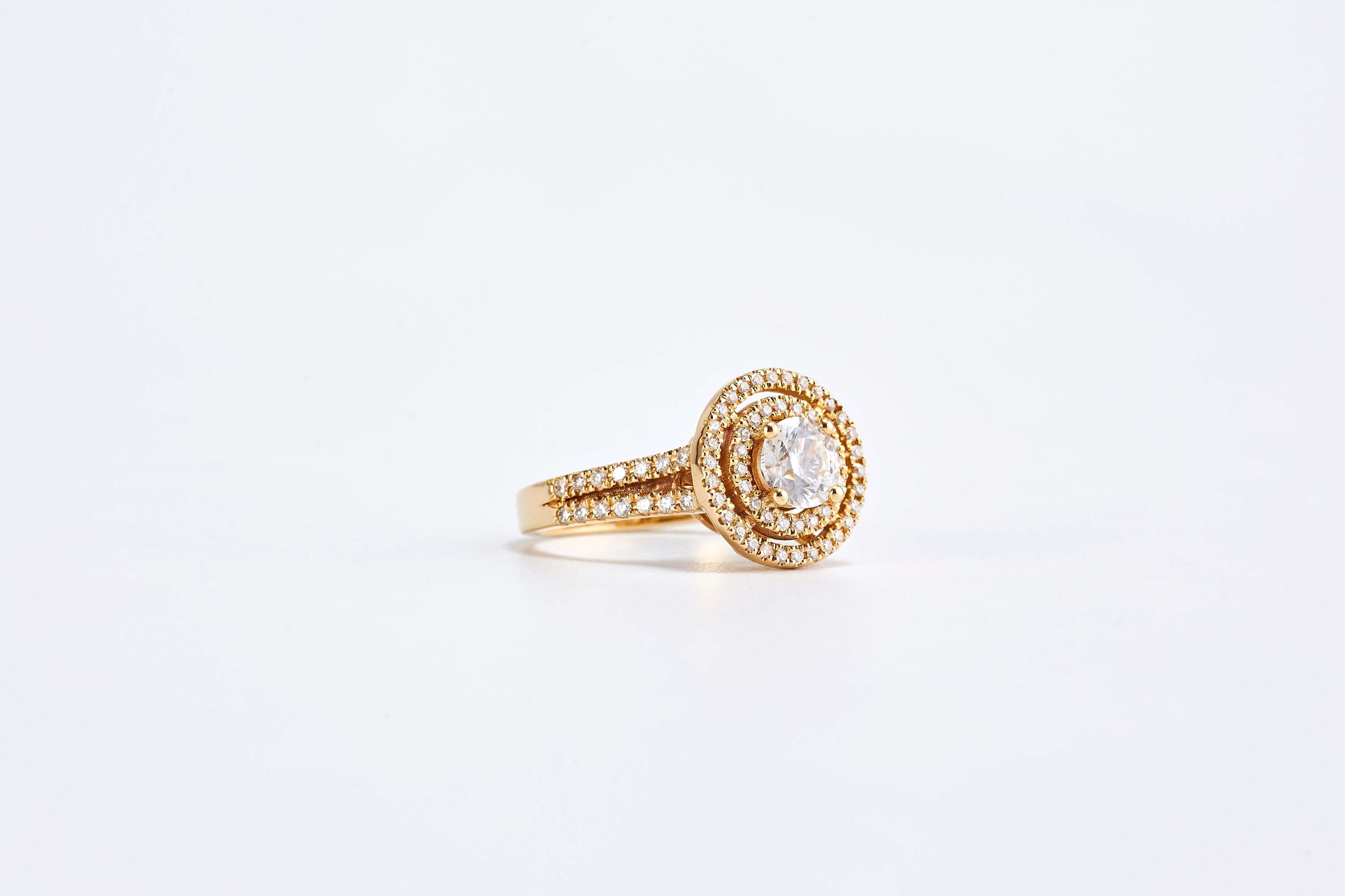 Engagement Ring with Central Round Cut Diamond and Double Halo in 18 Karat Yellow Gold
Designed around a central diamond, the double halo and pavé-set band are absolutely gorgeous.
Yellow gold,  Center stone 1.01 ct F VS1. Side diamonds are 1.05 ct