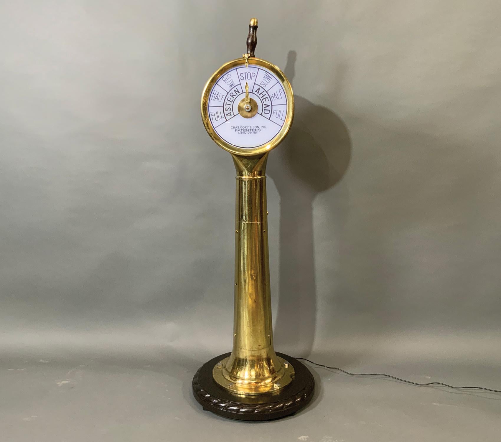 Solid brass ships engine order telegraph. This style has often used on yachts and tugboats. Showing astern and ahead commands showing slow, half and full. Varnished wood handle with brass cap. Mounted to a wood base. Note piece missing from bottom