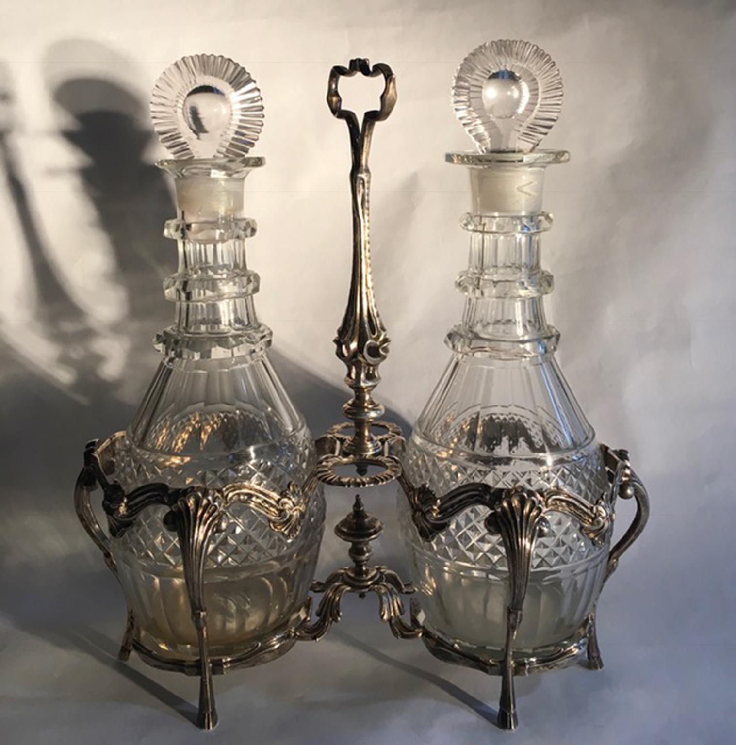 England Mid -18th century circa sterling silver and cut glass cruets service set in George IV style

The sterling silver basket of the two cut glass cruets is finely engraved. 
The two cruets are made in cut glass and the stoppers also. 
A piece