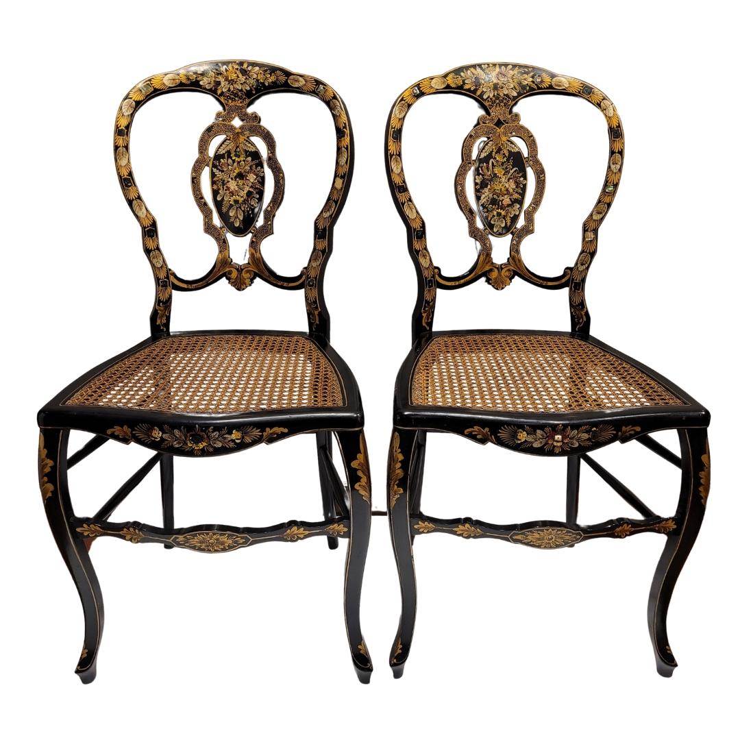 Exquisita y muy refinada pareja de sillas inglesas de principios del siglo XIX en madera lacada con incrustaciones de nácar y policromía dorada, de clara influencia asiática o filipina. El diseño calado del respaldo, con su medallón central, está