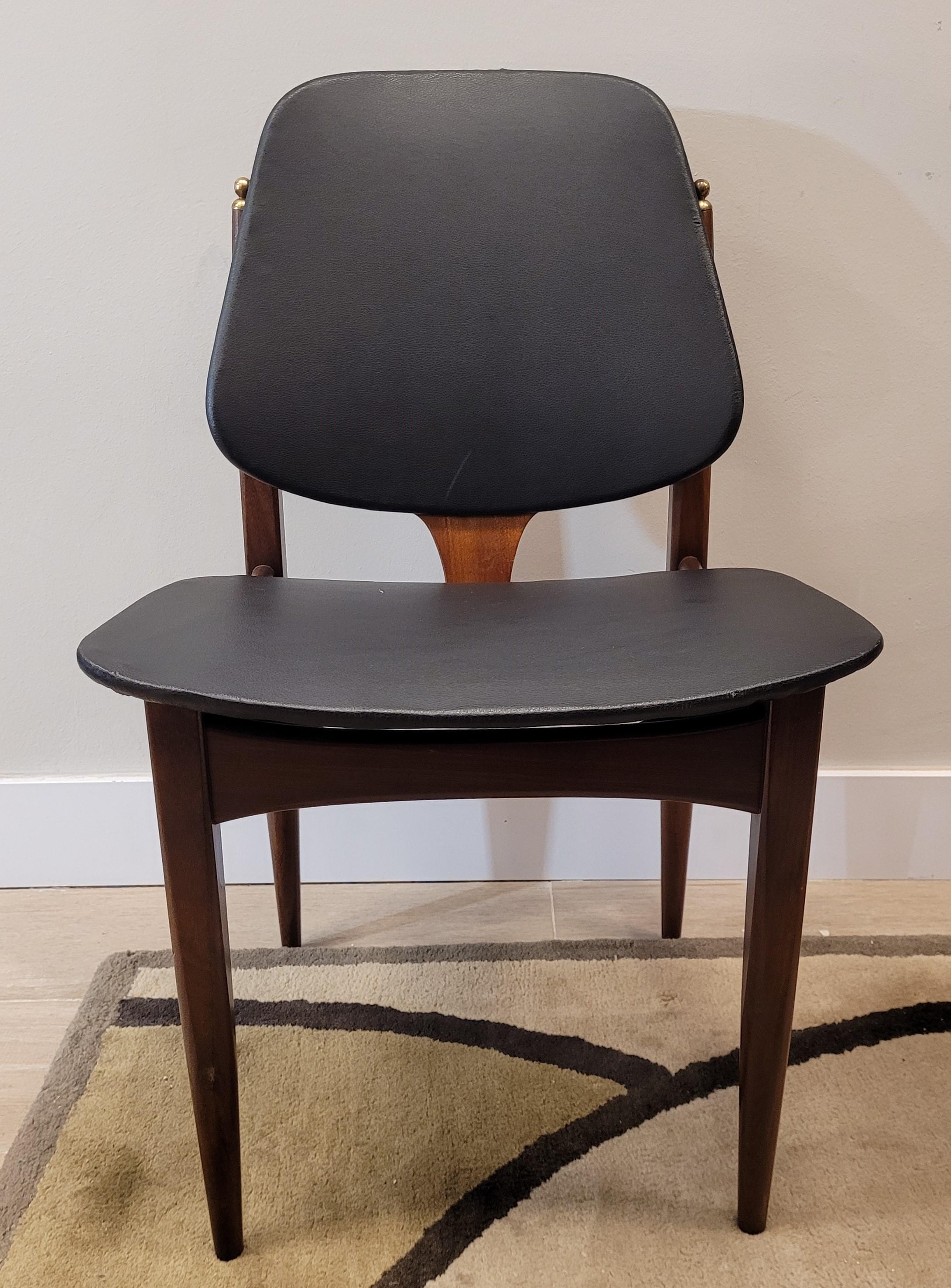 Exquisite and beautiful  pair of Midcentury design chairs made by the English factory Elliots of Newbury, in Berkshire. Each chair is structured with teak wood and is upholstered in black leather with a satin finish. Characteristic elements of
