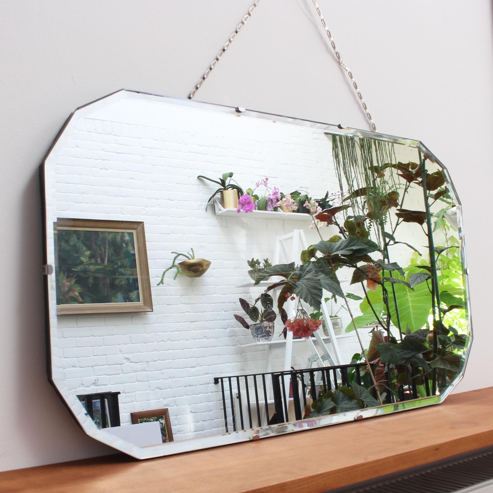 Midcentury English wall mirror with rare 12-sided shape (circa 1950s). With a horizontal orientation it has a linked-metal hanging chain. The mirror will have the effect of visually enlarging the room on whose wall it hangs. It is a classic mirror