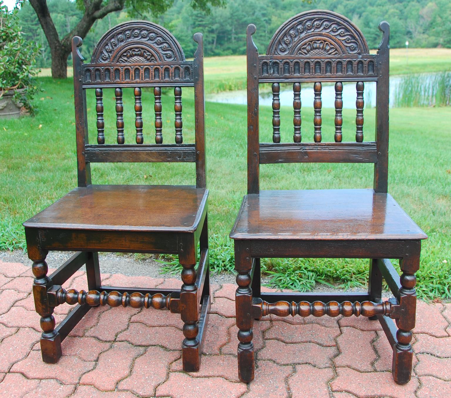English period Charles II pair of oak carved side chairs, referred to as back stools in this era. These 17th century chairs have wonderful hand-turned spindles and chisel carved back with sunflower, lunettes and rope and circle motifs. These were