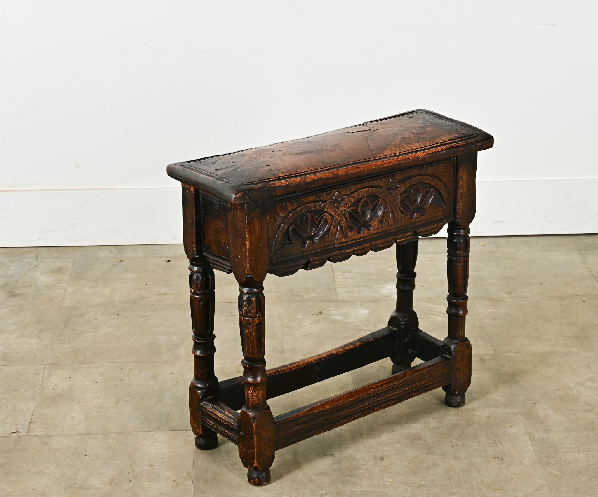 Ce tabouret ou table d'appoint en chêne massif de style anglais Jacobean, fabriqué à la fin des années 1600, est assemblé à l'aide de chevilles. Le plateau rectangulaire à une seule planche repose sur un tablier festonné et sculpté à la main avec