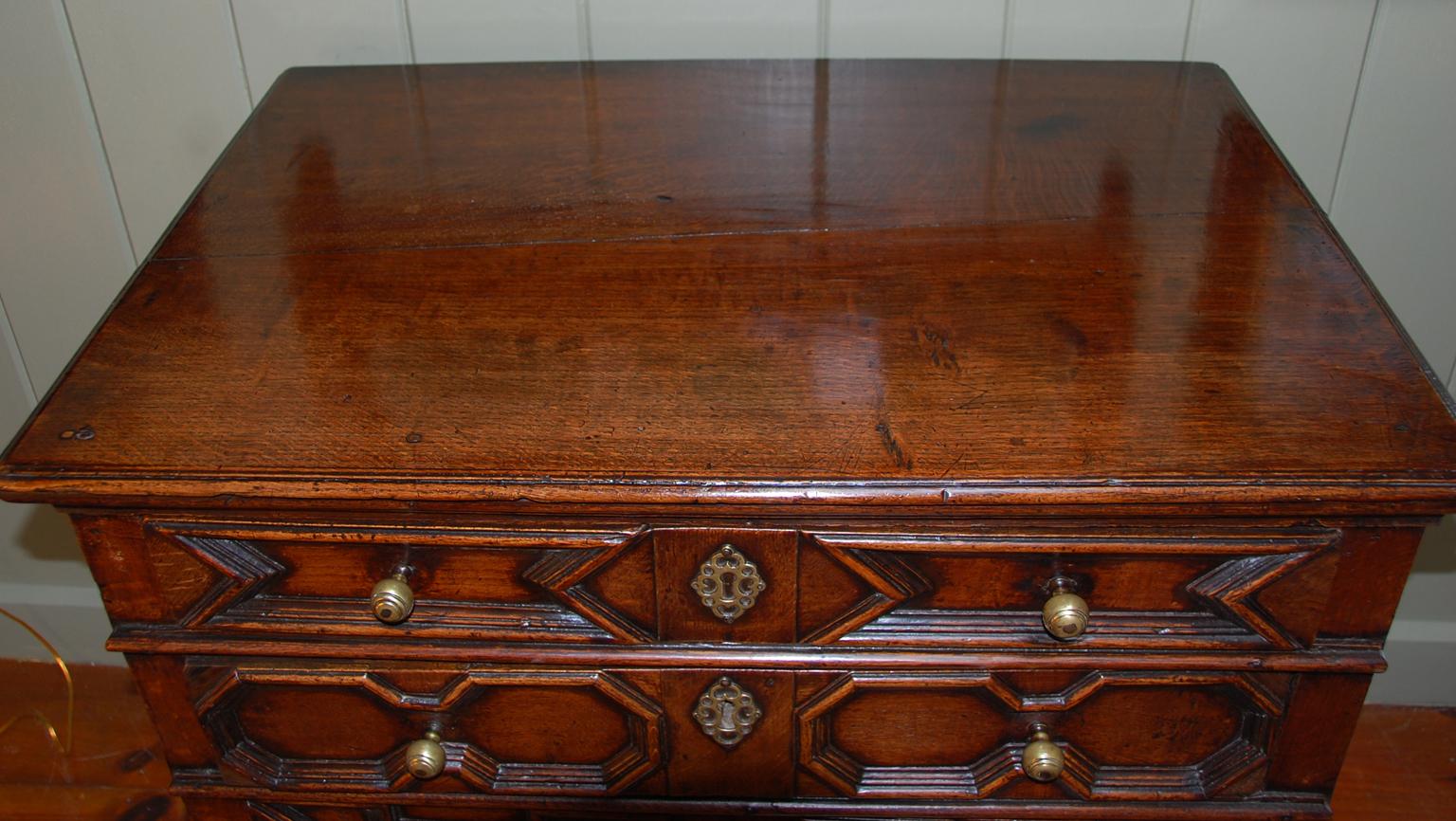 English 17th century William and Mary period oak paneled chest of four graduated drawers, deep patination, never refinished, bold moldings to drawers. The original side rails upon which the drawers originally ran have been replaced, as have the bun