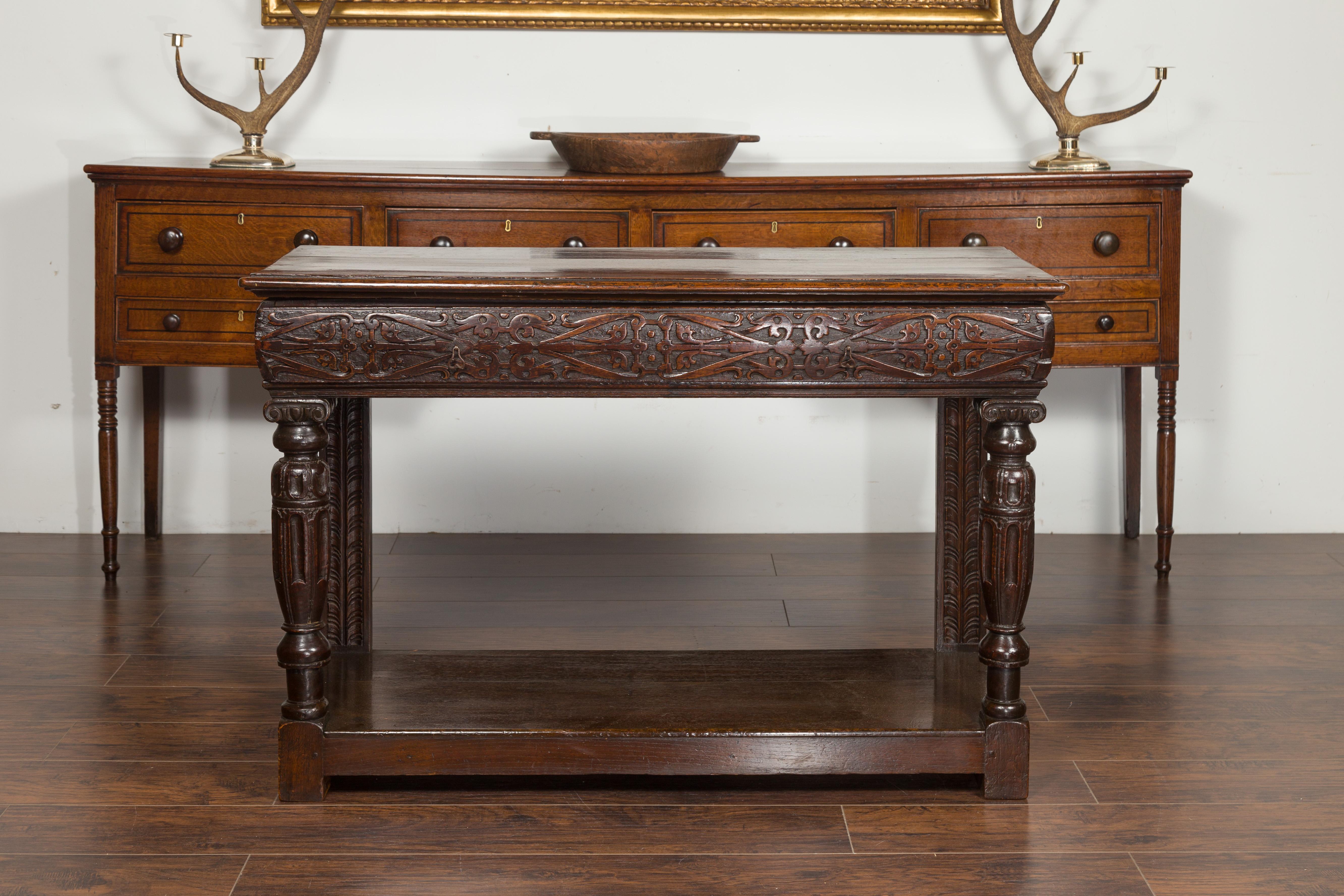 An English George III period oak console table from the early 19th century, with carved drawer and Ionic capitals. Created in England during the early years of the 19th century, this oak console table features a rectangular planked top sitting above