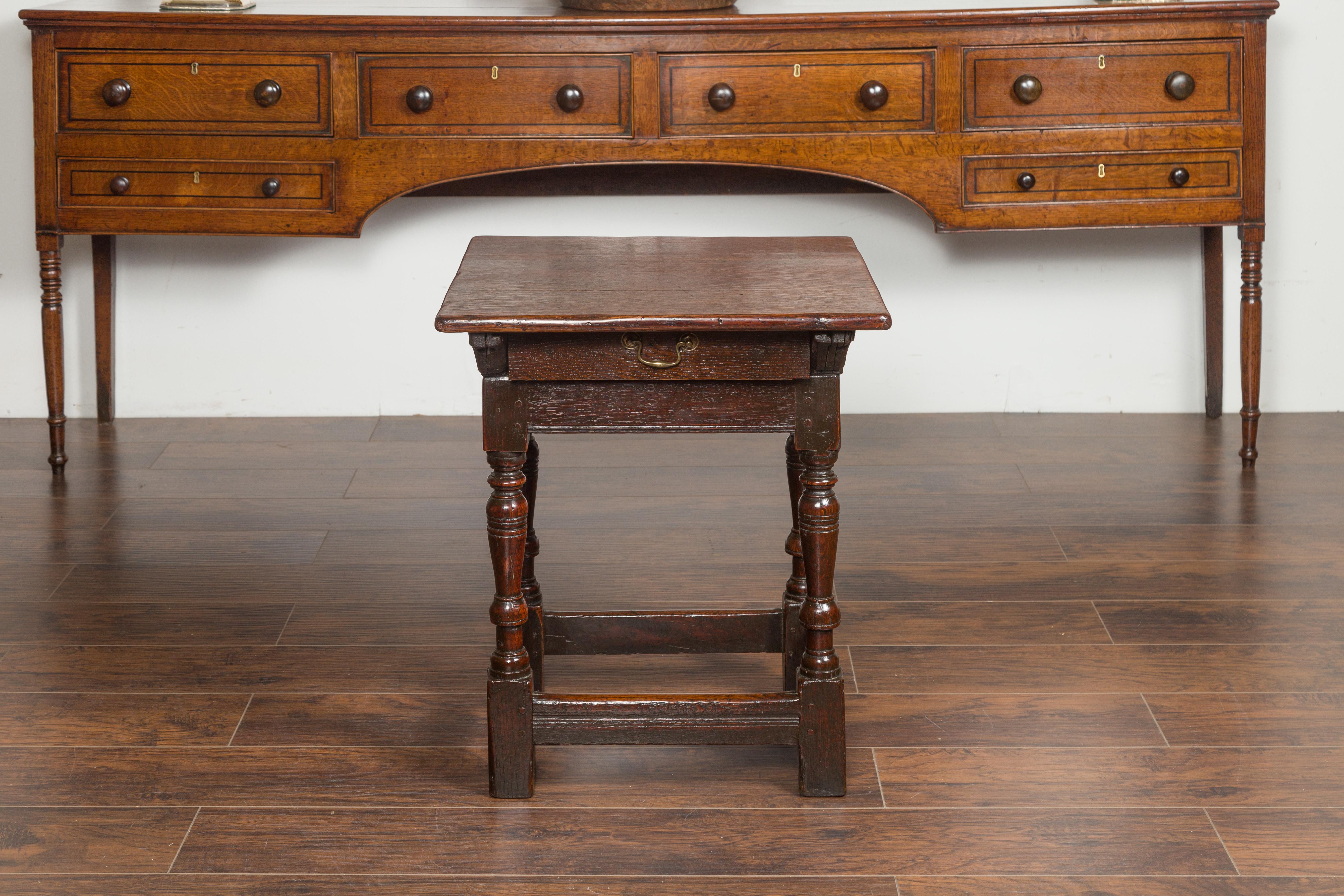 Table d'appoint en chêne d'époque géorgienne anglaise du début du 19e siècle, avec un seul tiroir, des pieds tournés et des traverses. Née en Angleterre au début du XIXe siècle, cette table d'appoint en chêne présente un plateau carré au-dessus d'un