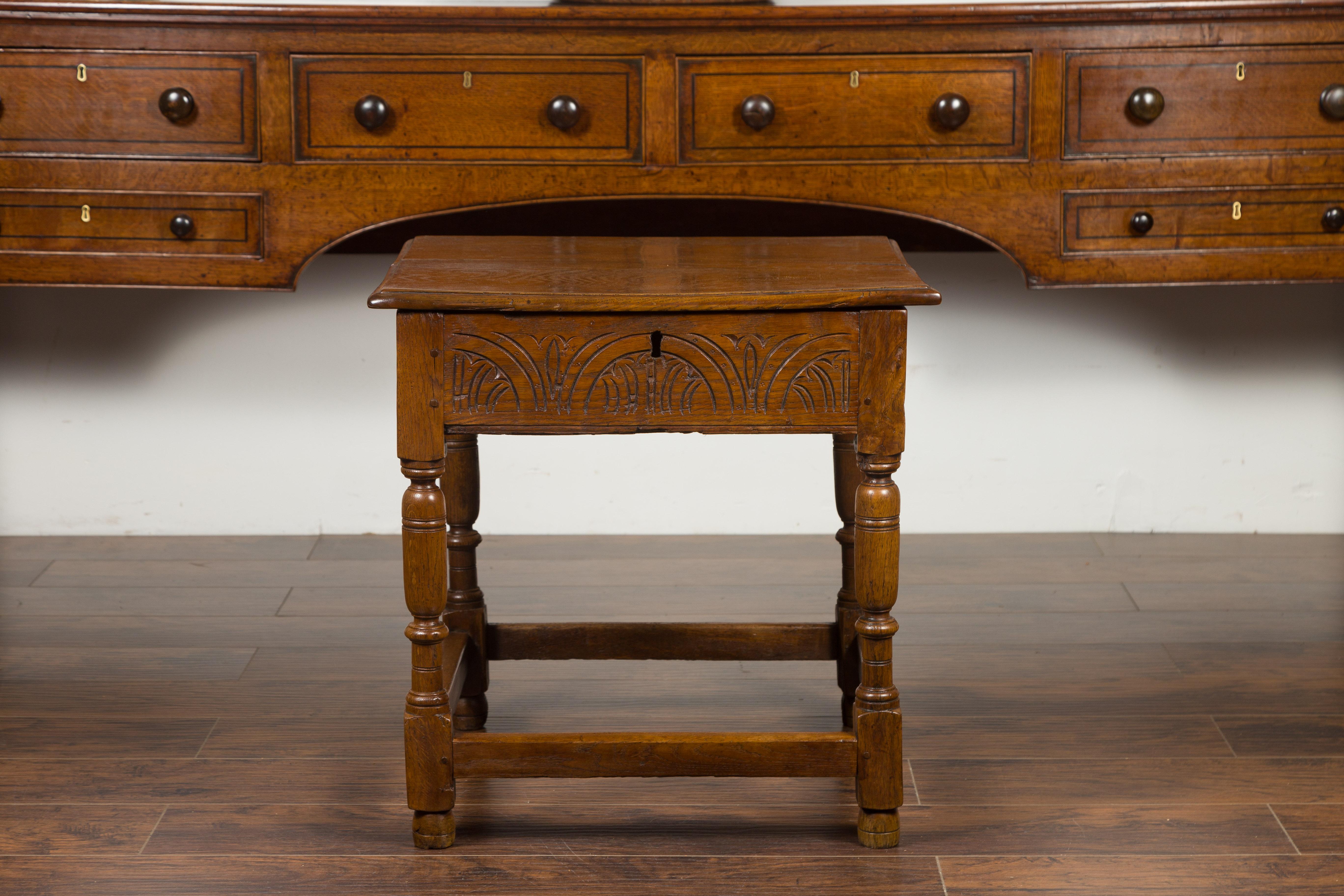 An English Georgian period oak table from the early 19th century, with lift top and turned base. Born in England during the reign of George III, this oak table features a rectangular top that lifts up to reveal a convenient storage space. Carved on